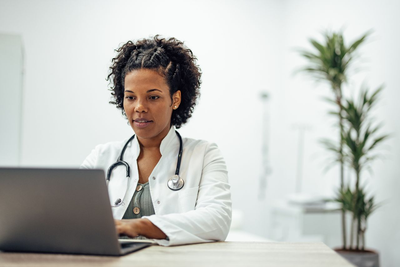 Female doctor sitting at desk working on laptop