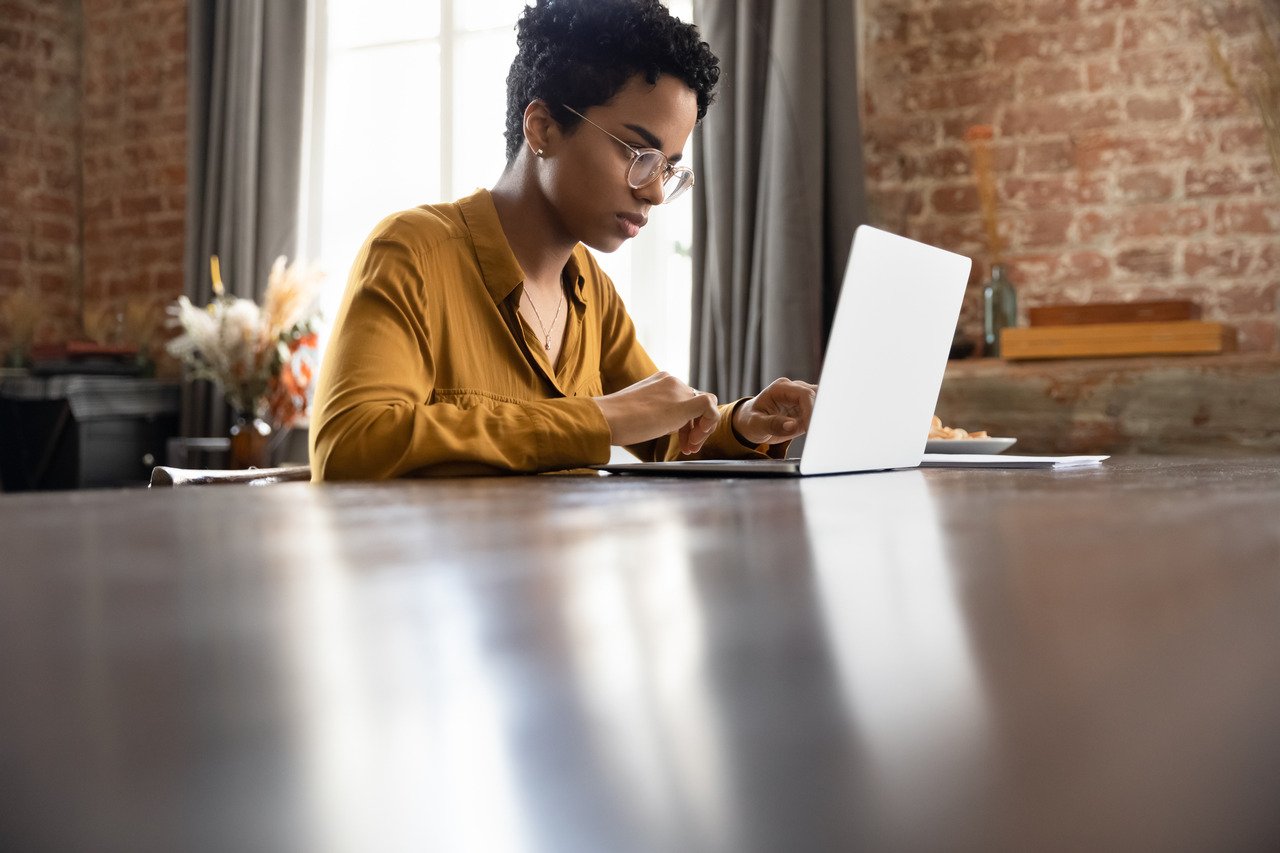 Black female using laptop while sitting at kitchen table