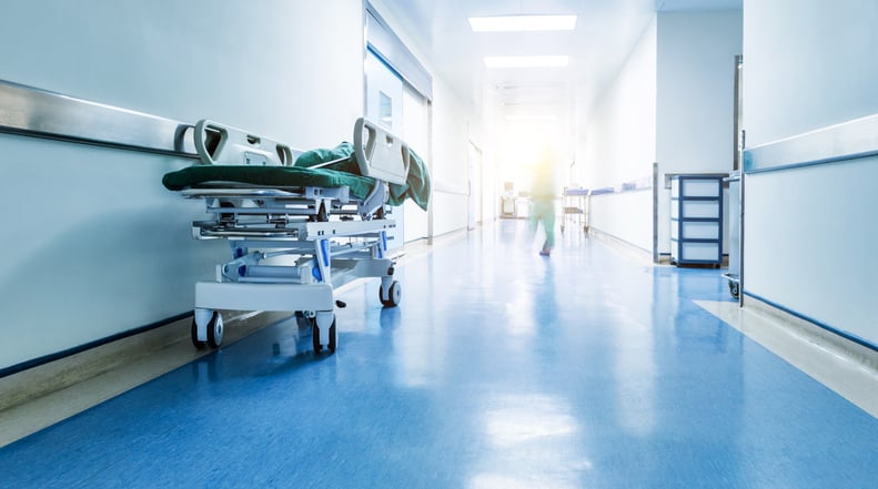 A hospital hallway with a stretcher and blurred nurses