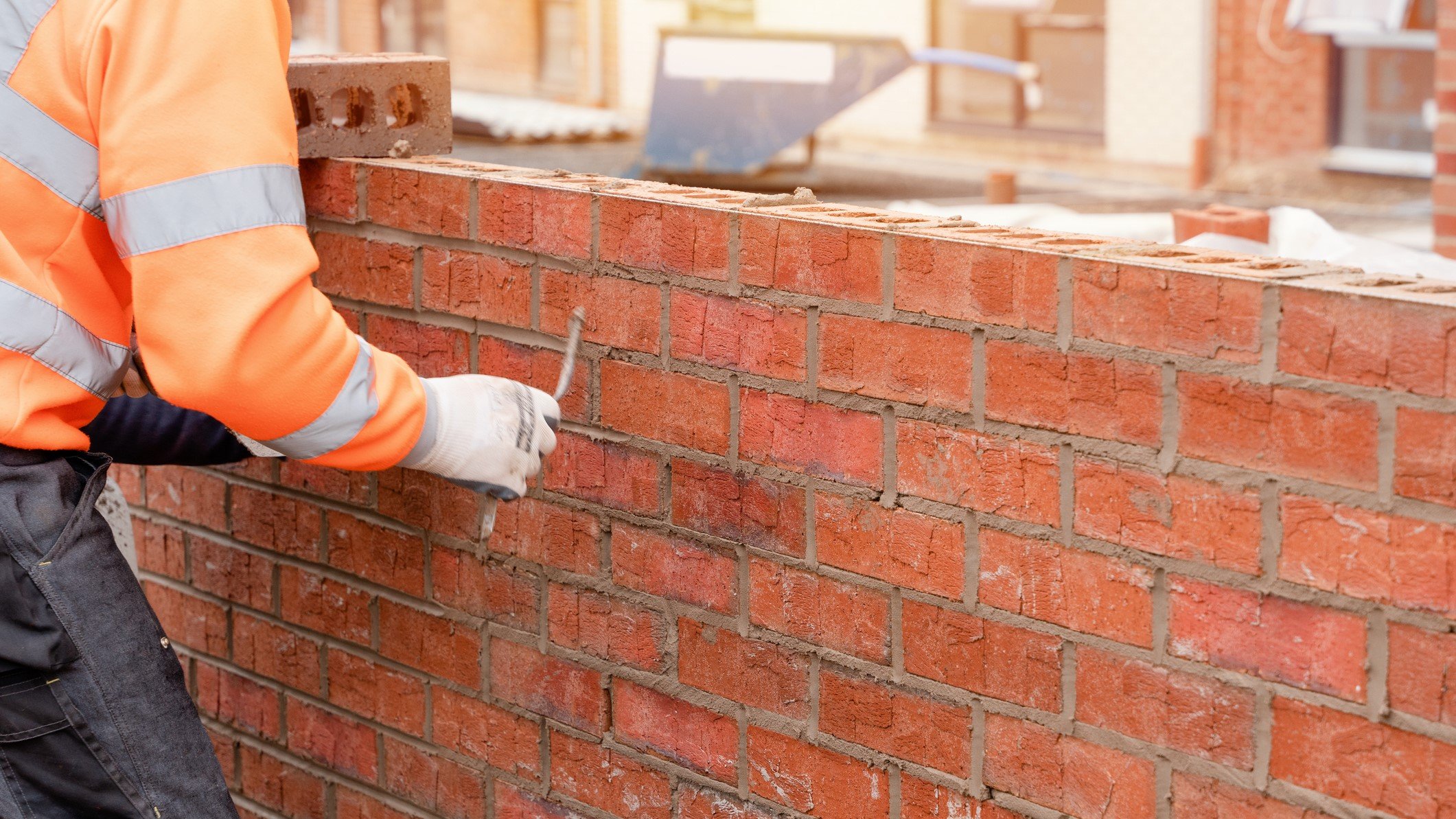 Photo of a construction worker sealing a layer of brick
