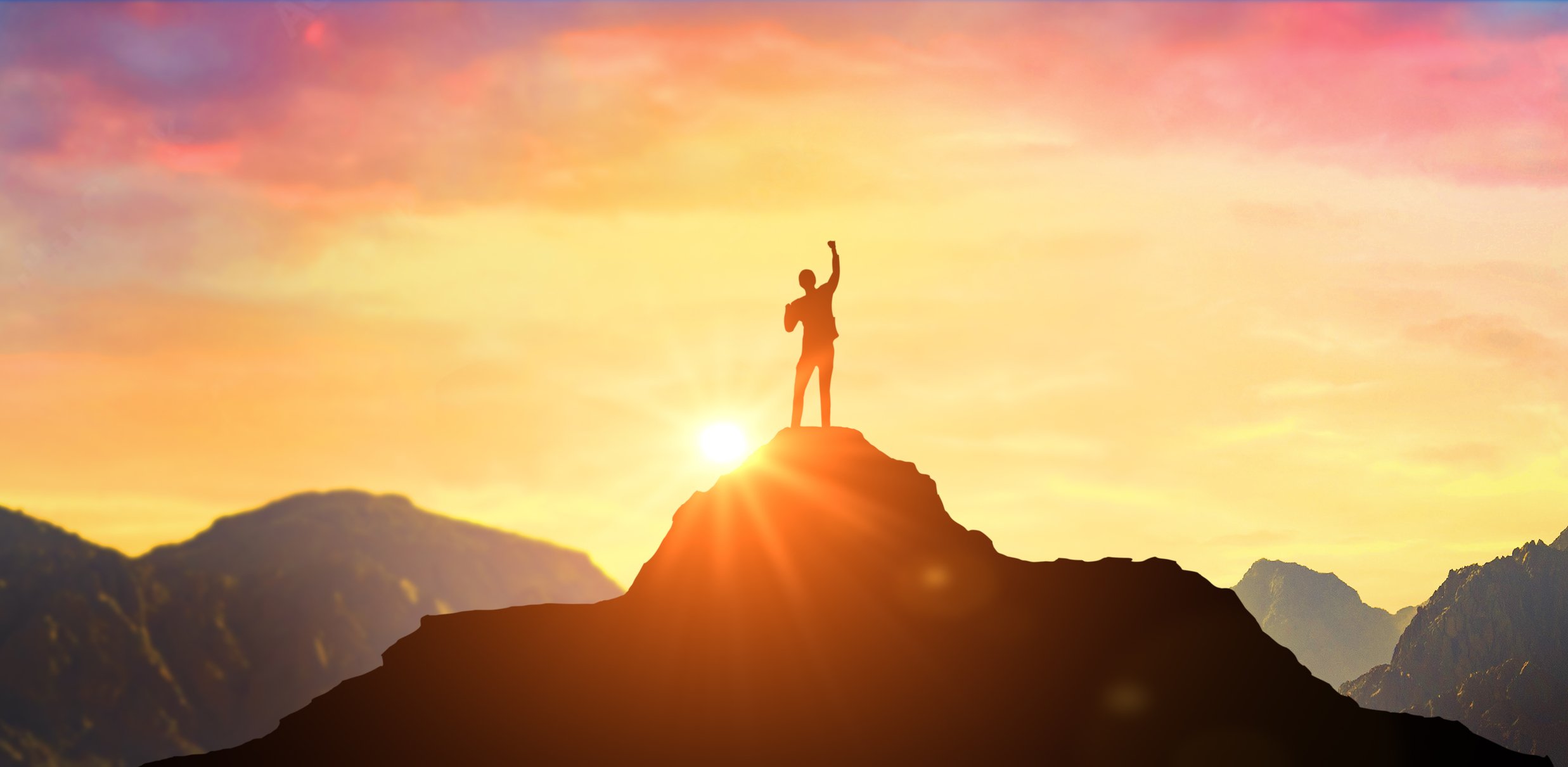 Photo of a person celebrating at the top of the mountain while the sun setsrises