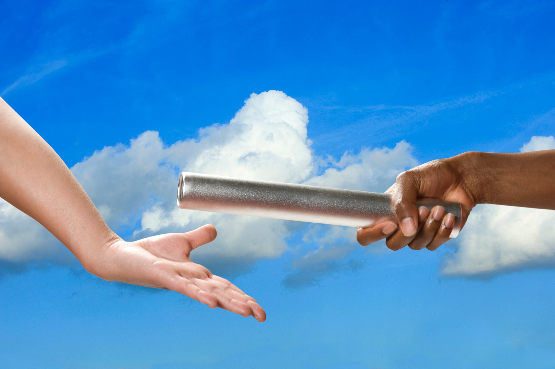 two people handing off a baton with a sky background