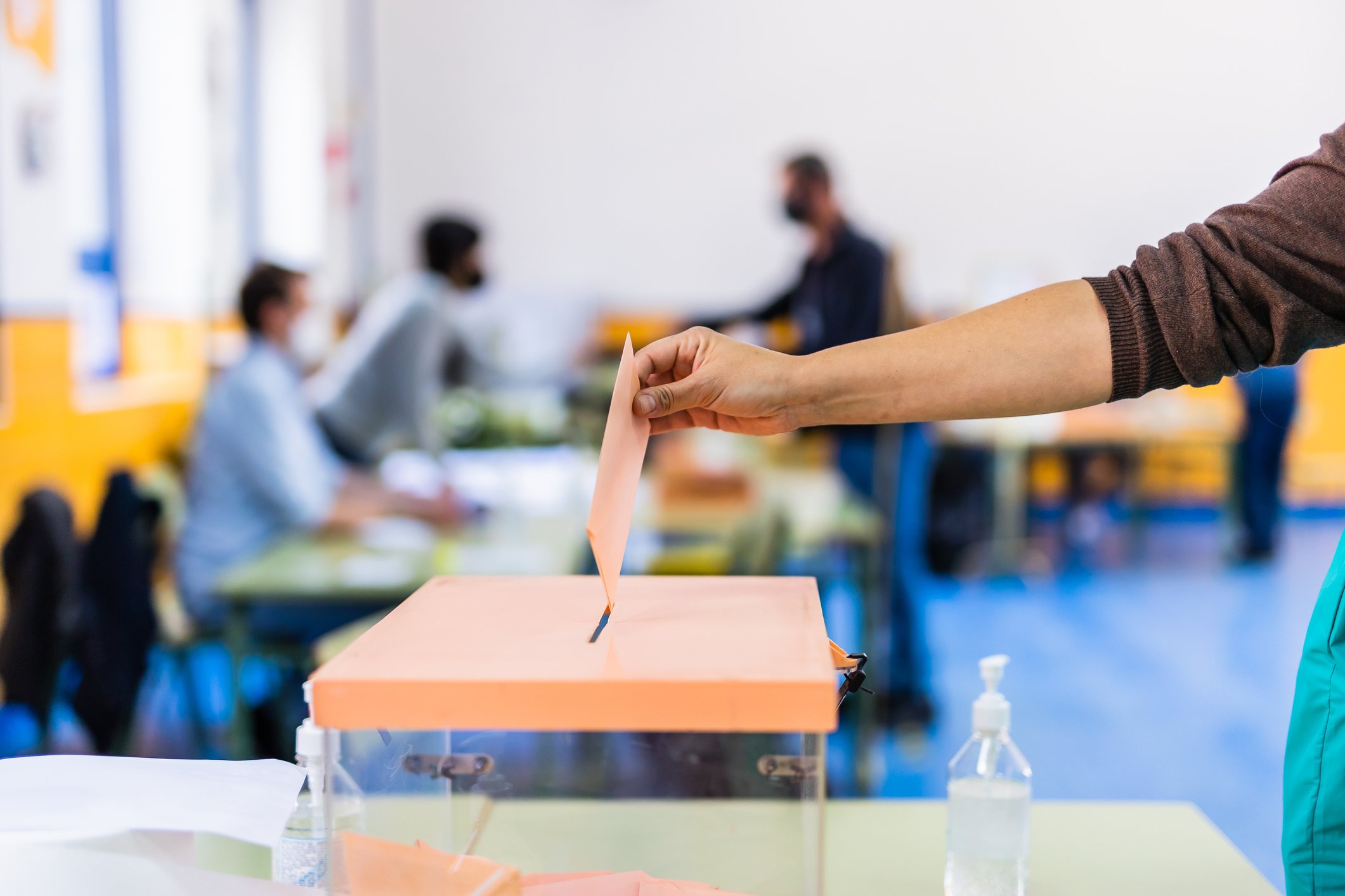 Hand posing an envelop in a ballot box for elections