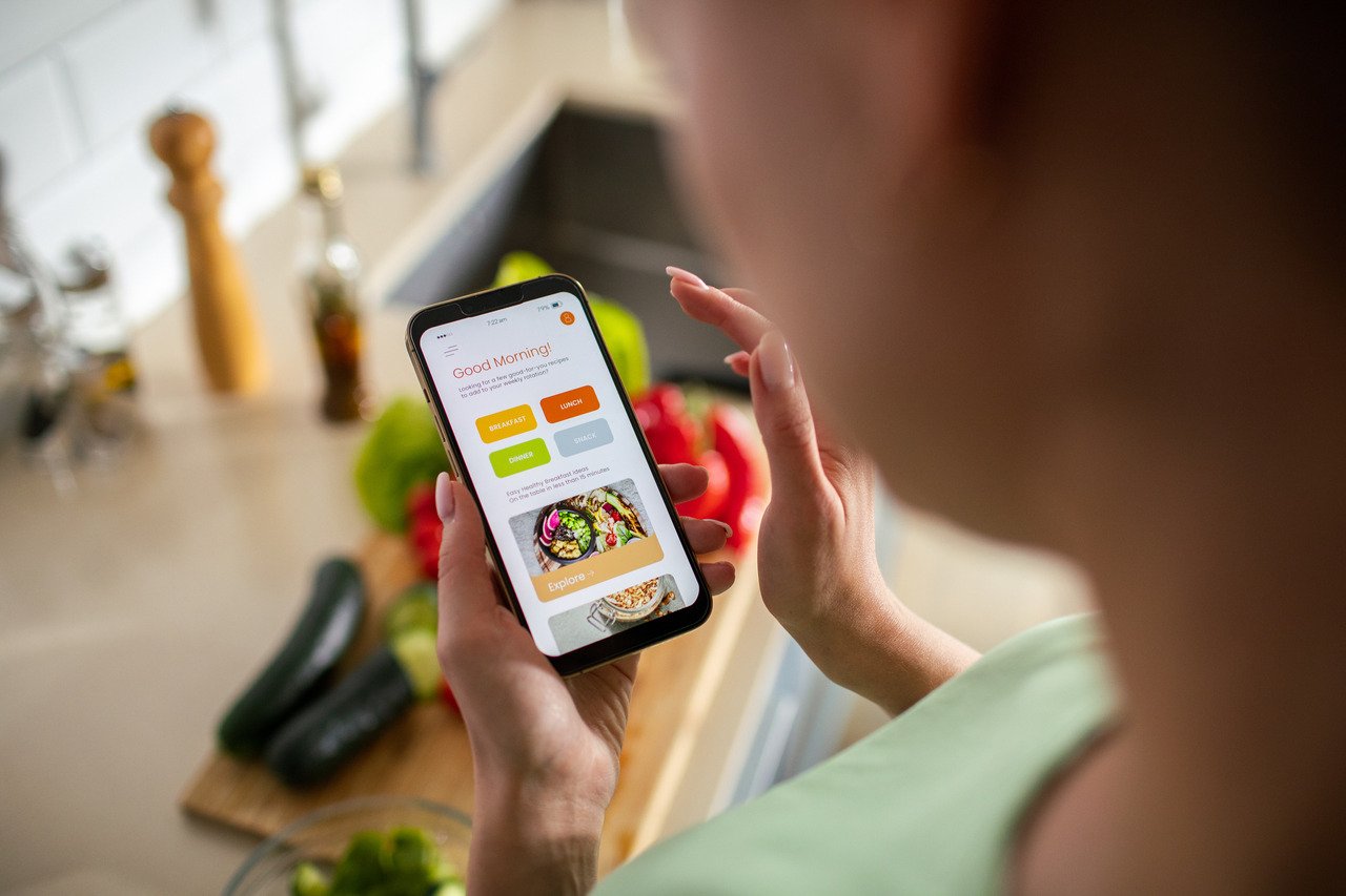 woman using weight loss app while preparing a meal