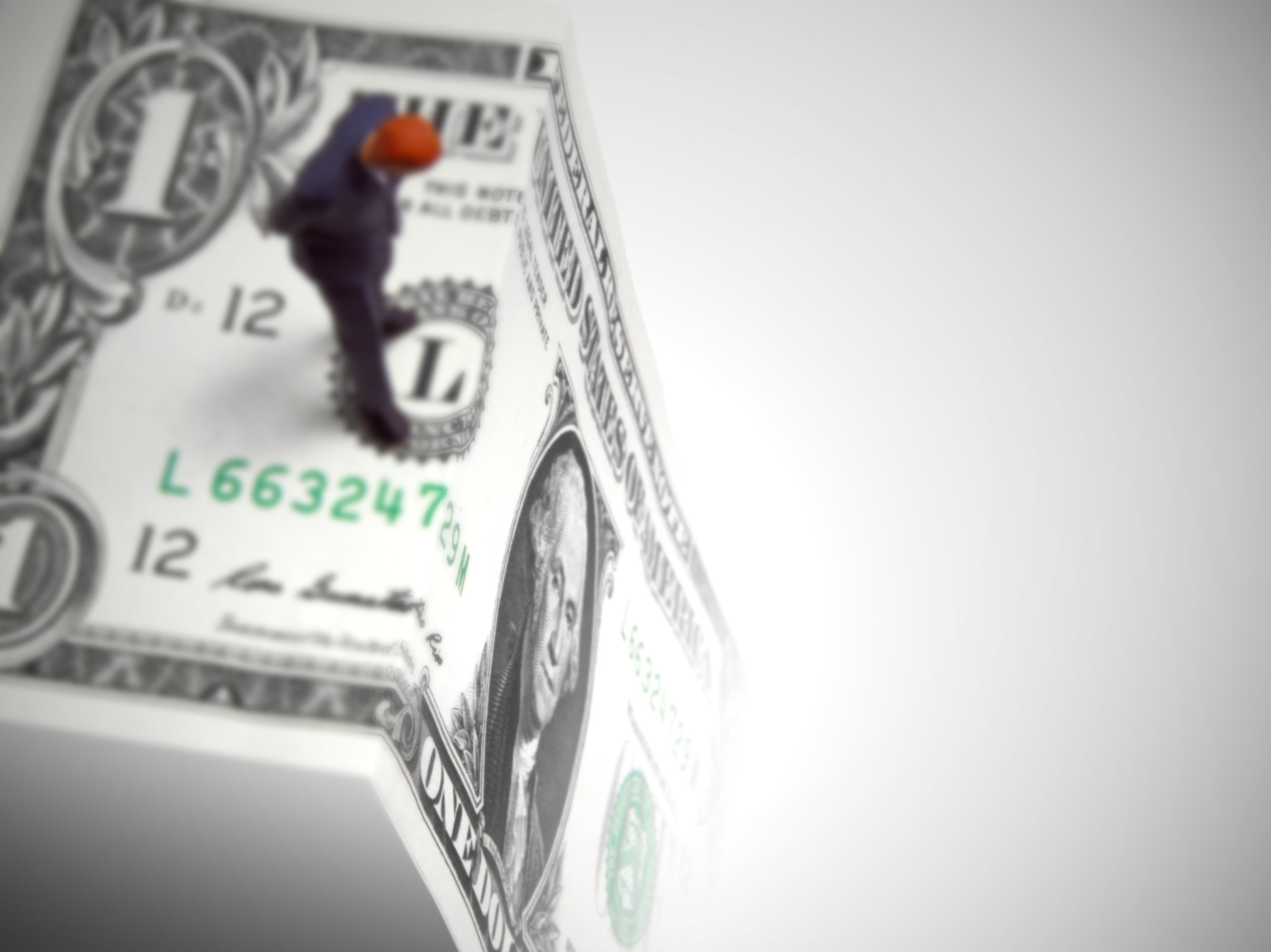 A man standing on the edge of a one dollar bill