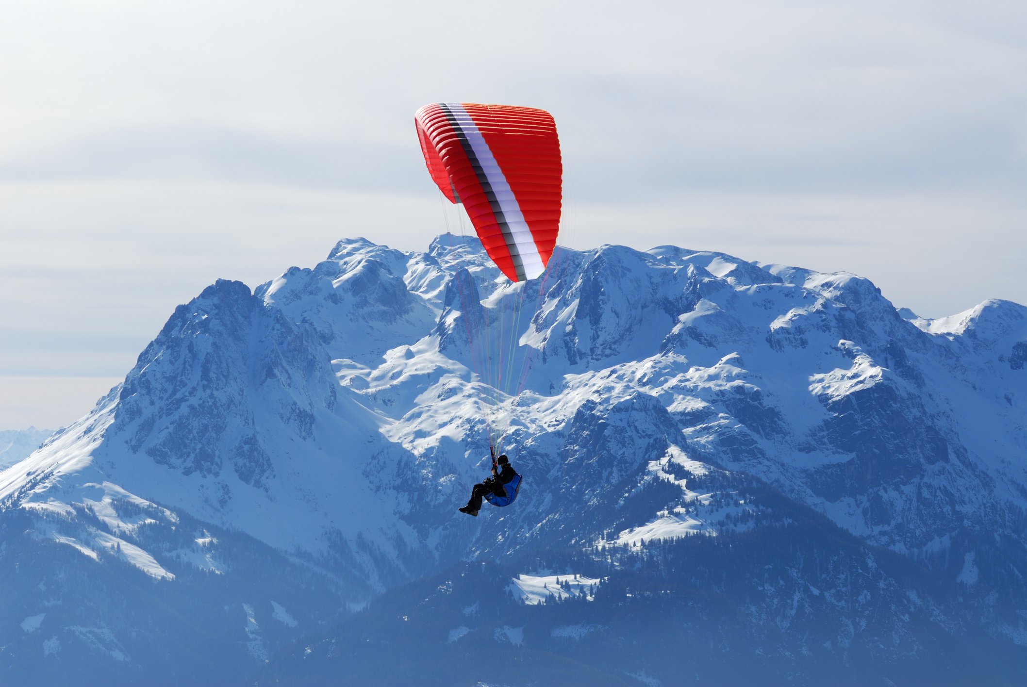photo of a paraglider in the foreground with the alps in the background