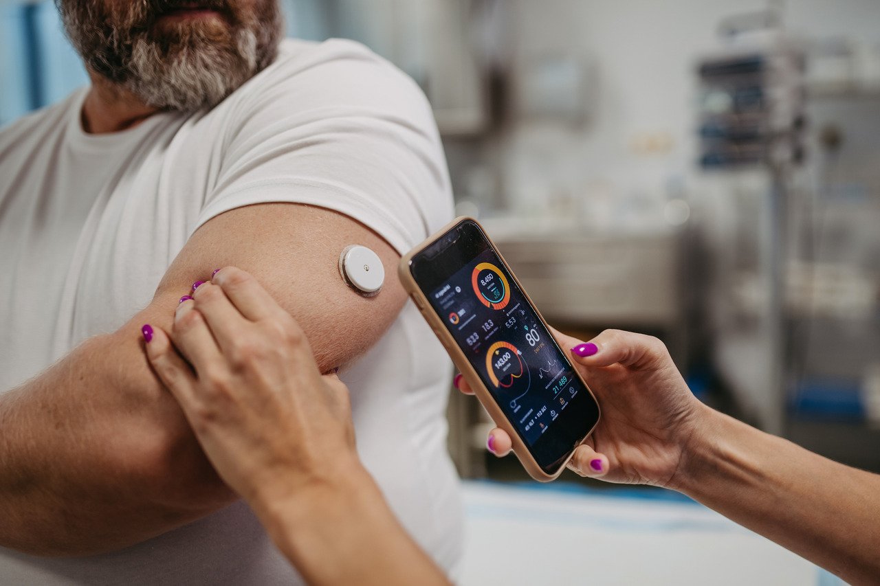 man checks blood sugar level with continuous glucose monitor and smartphone app