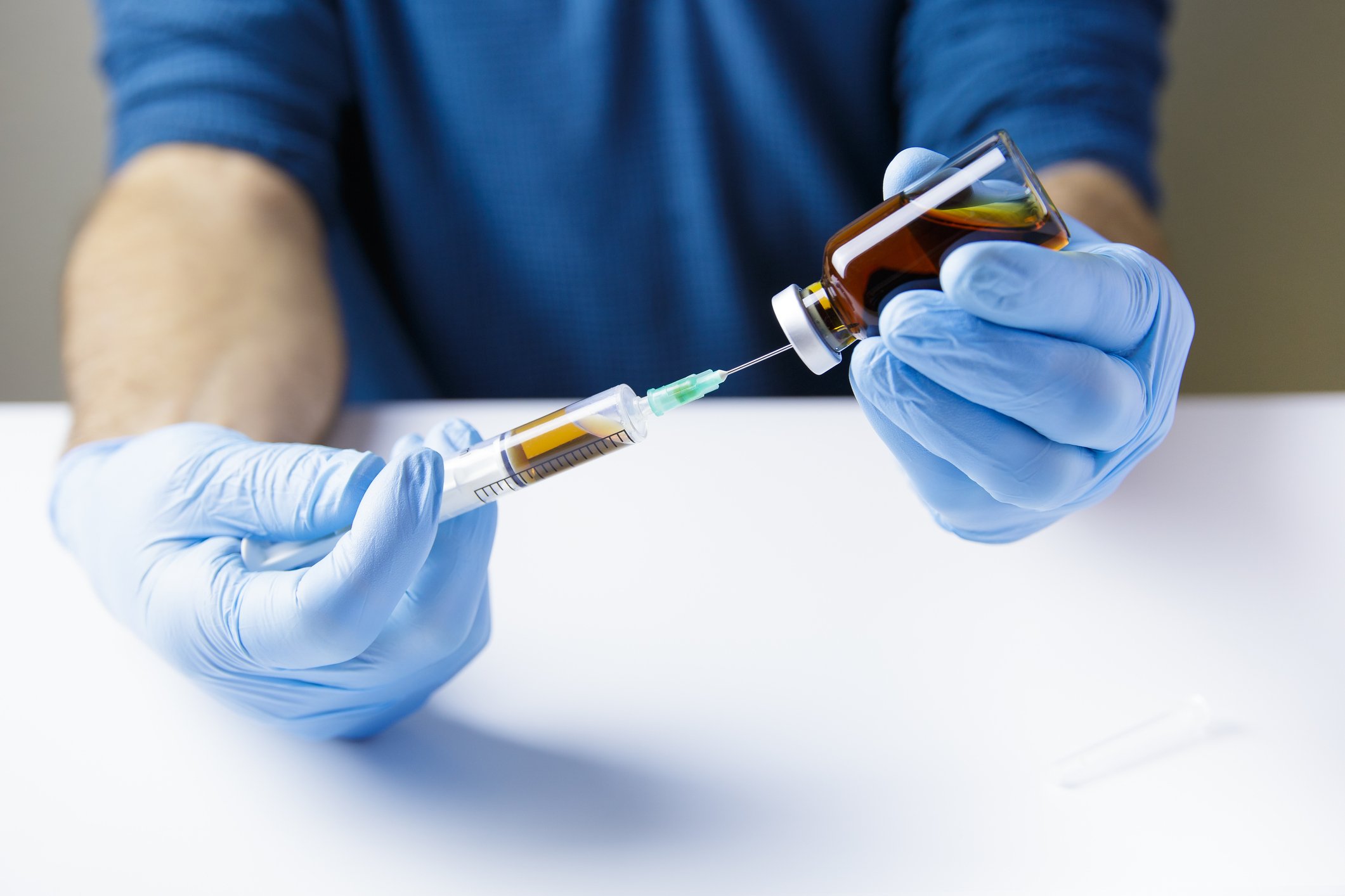 Doctor or nurse is inserting syringe into bottle of injectable medication