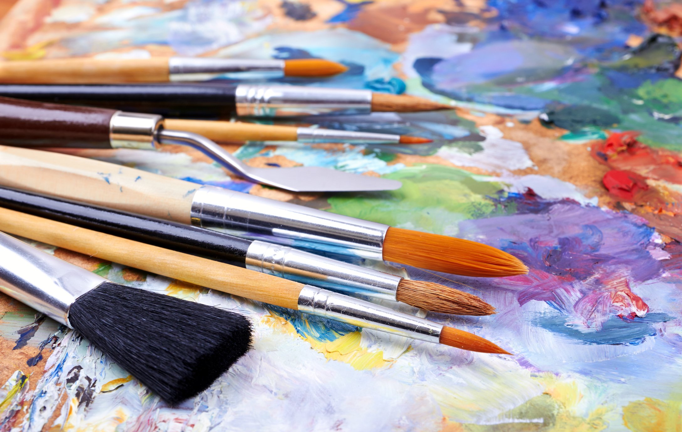 Paint brushes sitting on a colorful canvas