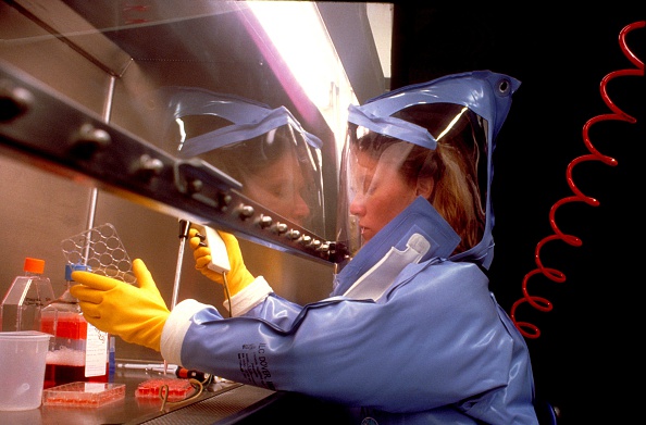 Scientist performing tests while wearing a biohazard suit with full face shield and gloves Image courtesy CDC 1974 Photo