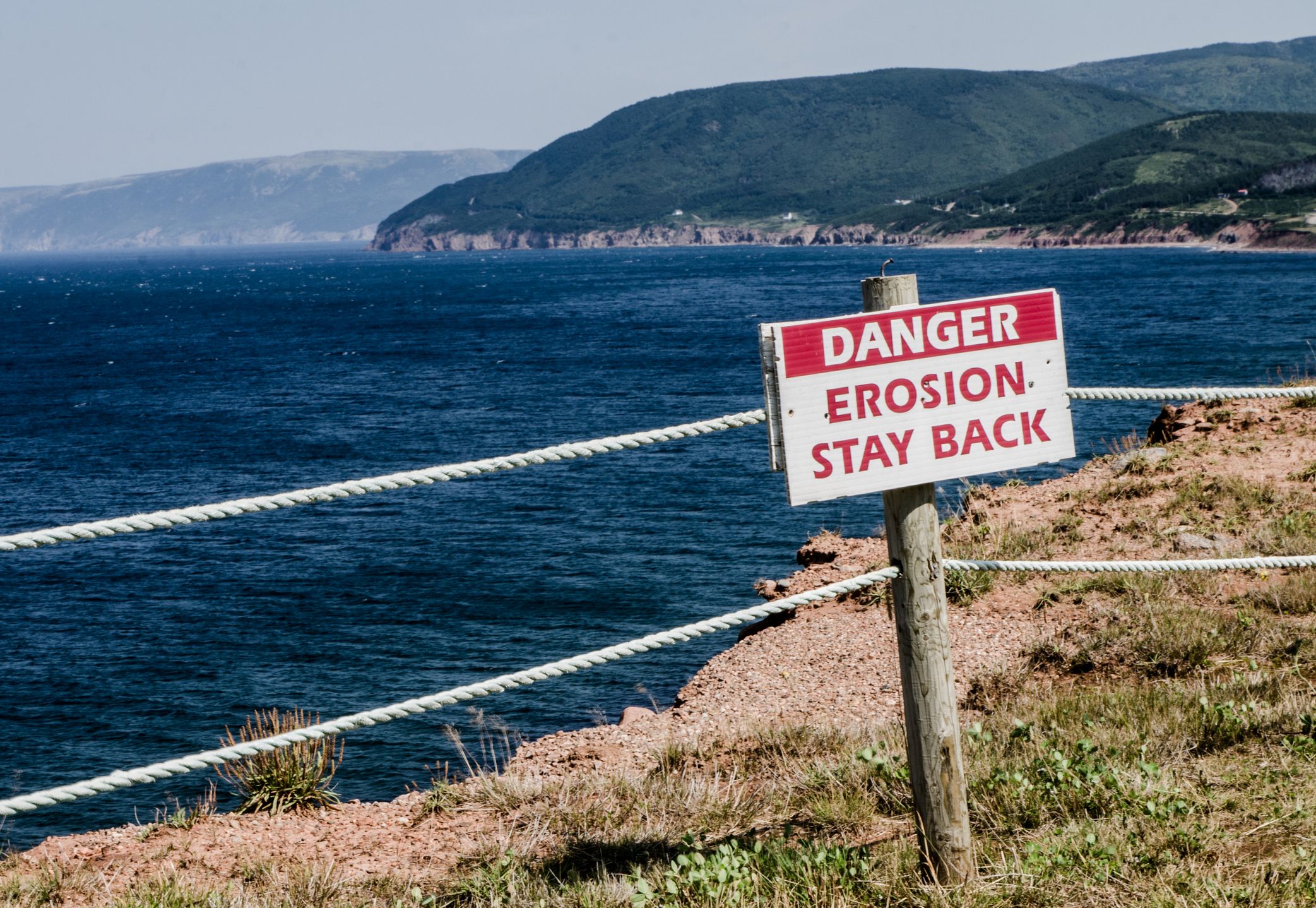 Sign warning about erosion on a cliff