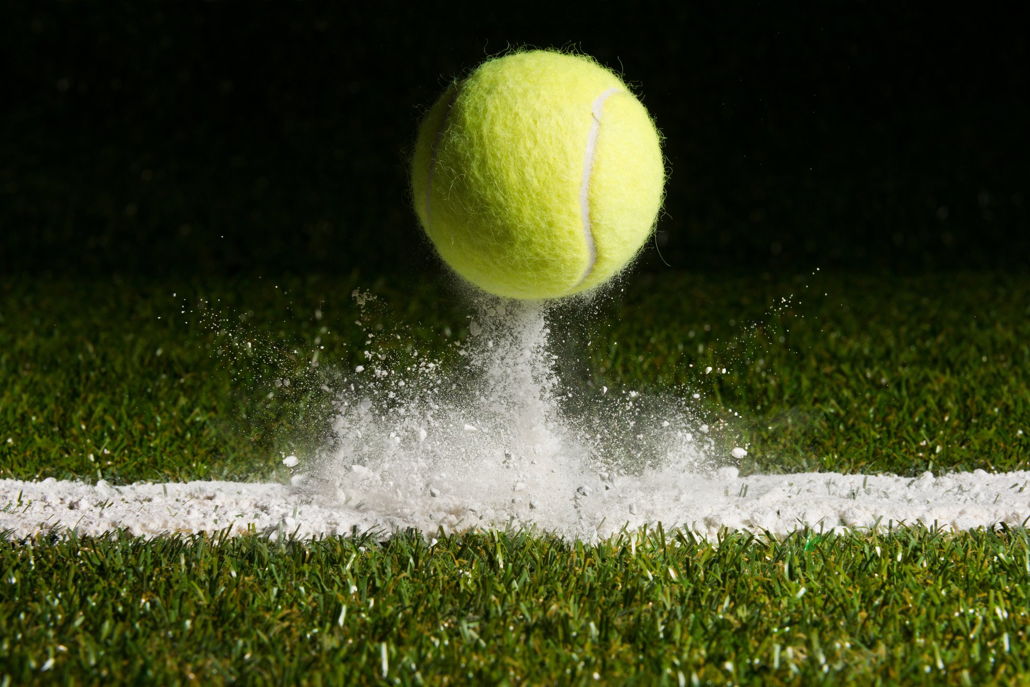 Close-up shot of a tennis ball hitting the line chalk