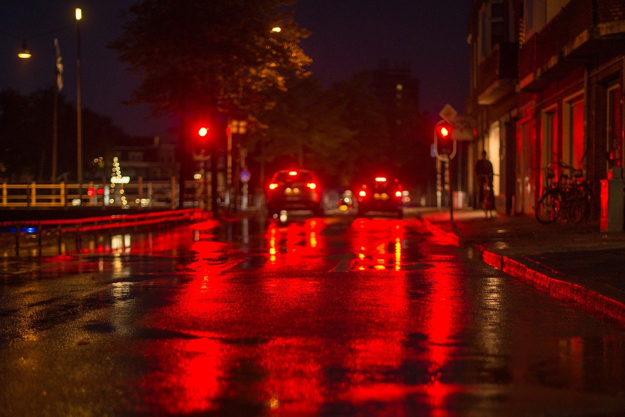 Traffic at a red stoplight brake lights reflected in wet road