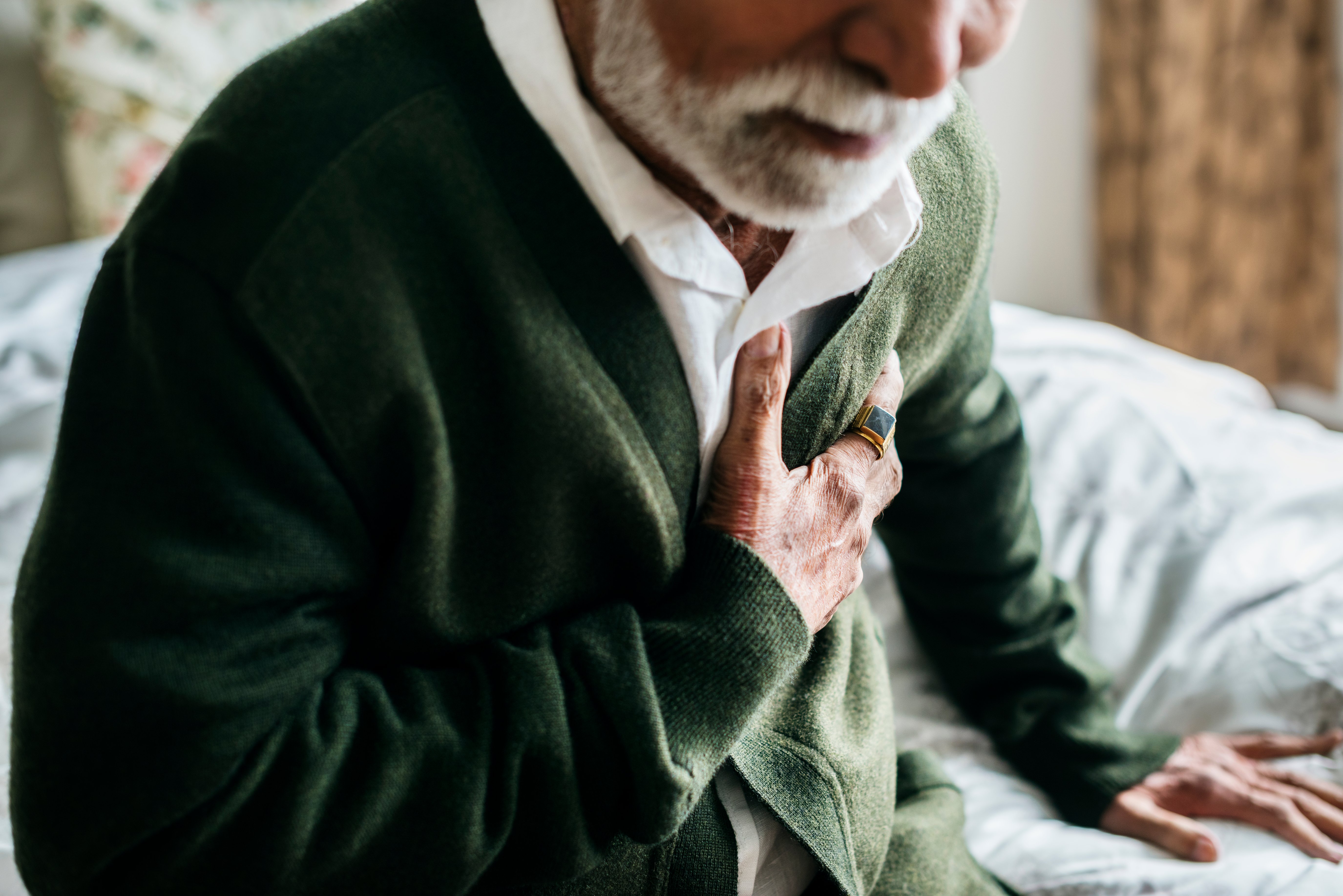 photo of elderly man having heart problems holding his chest