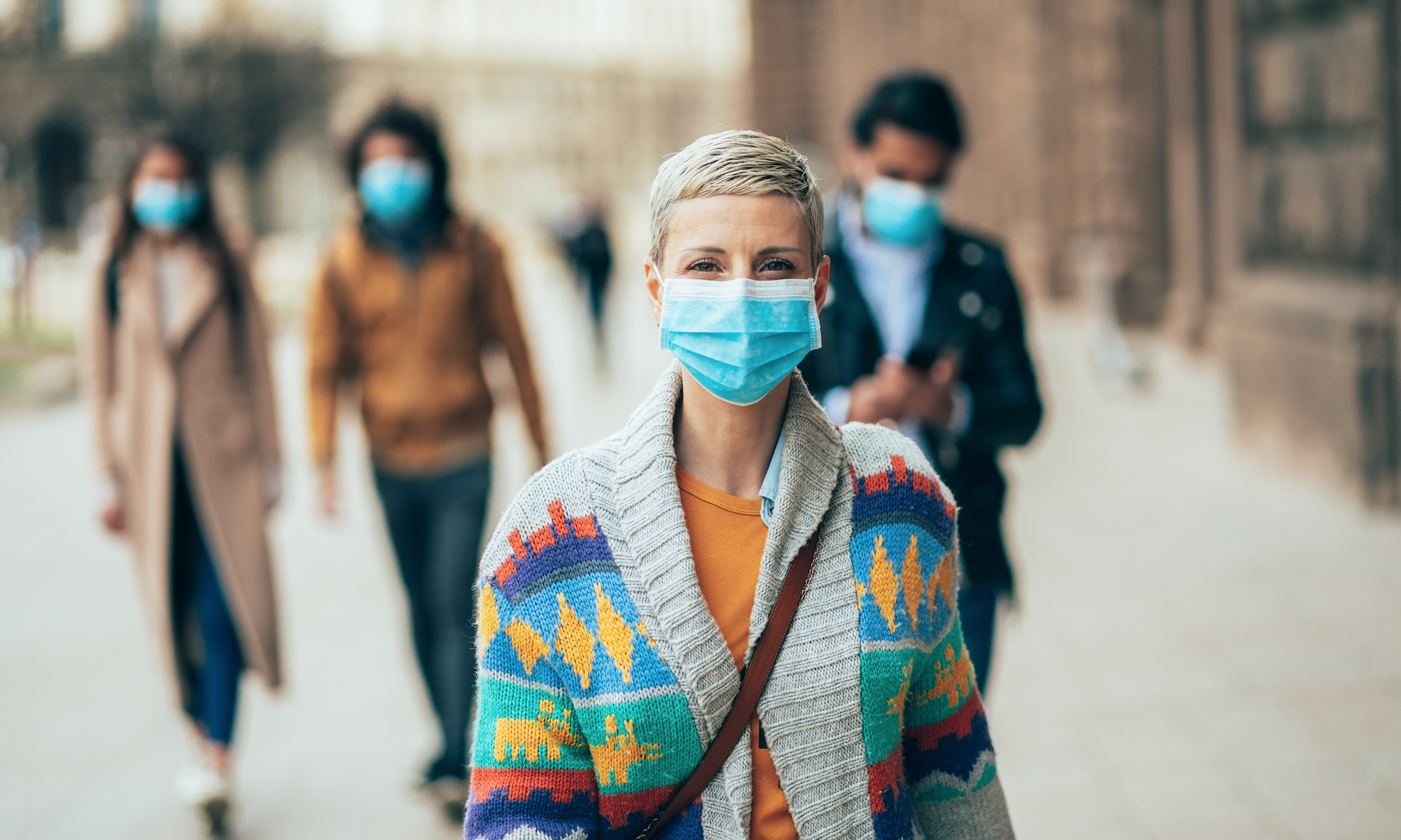 A woman is wearing a face mask on the sidewalk
