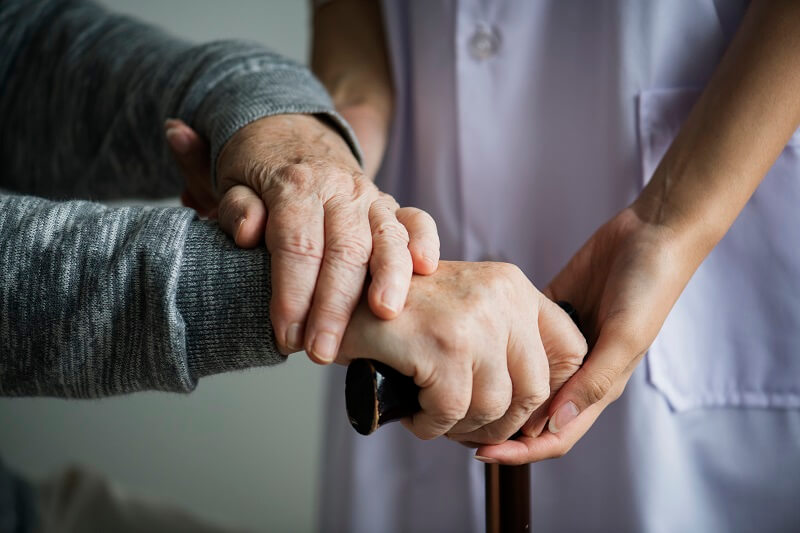 A nurse holding the hands of an elderly patient