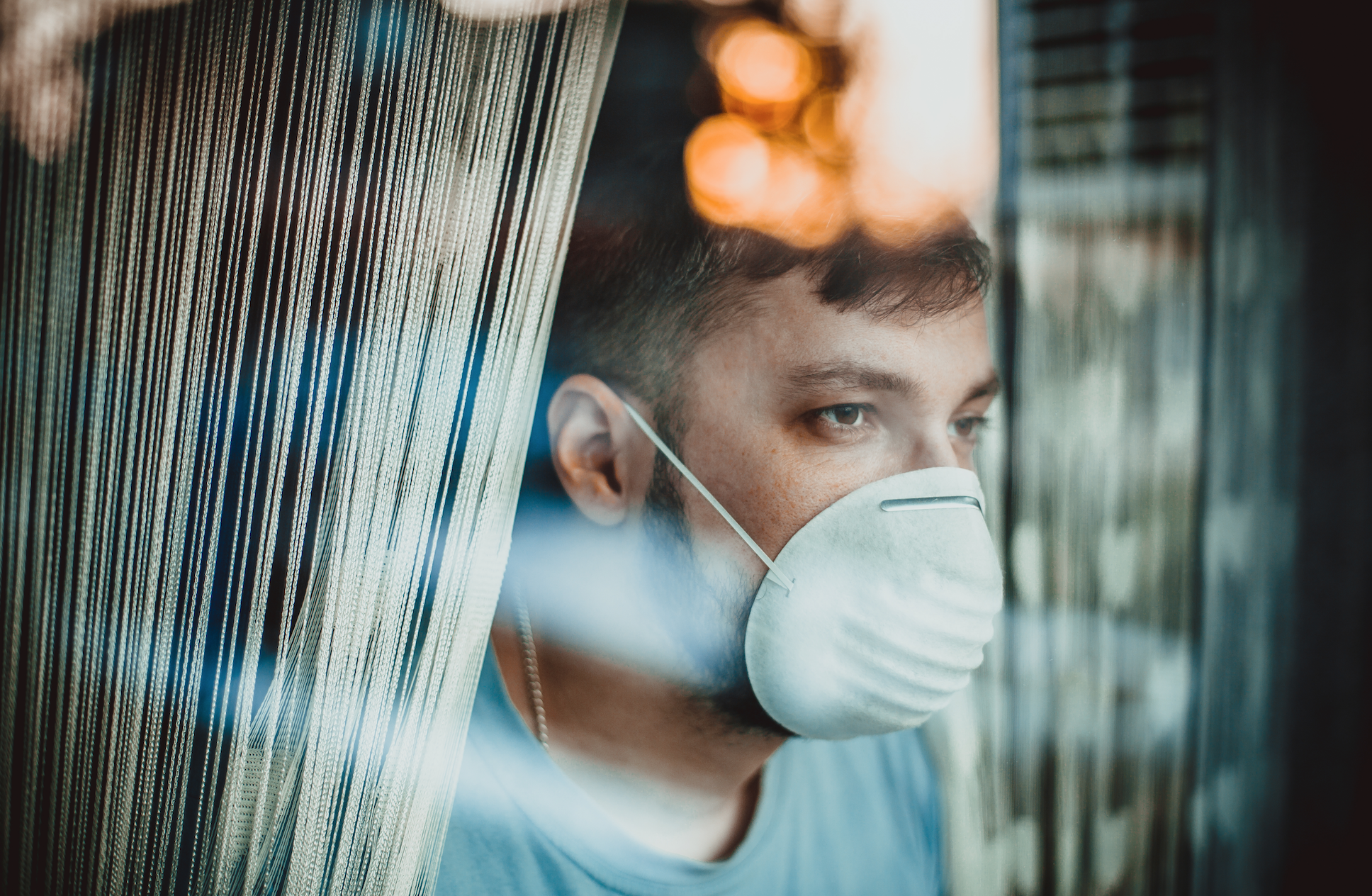 A patient with a surgical mask looks out a window