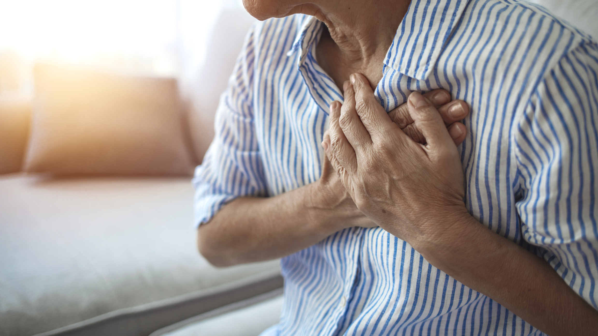 A woman holds her chest to indicate chest pain