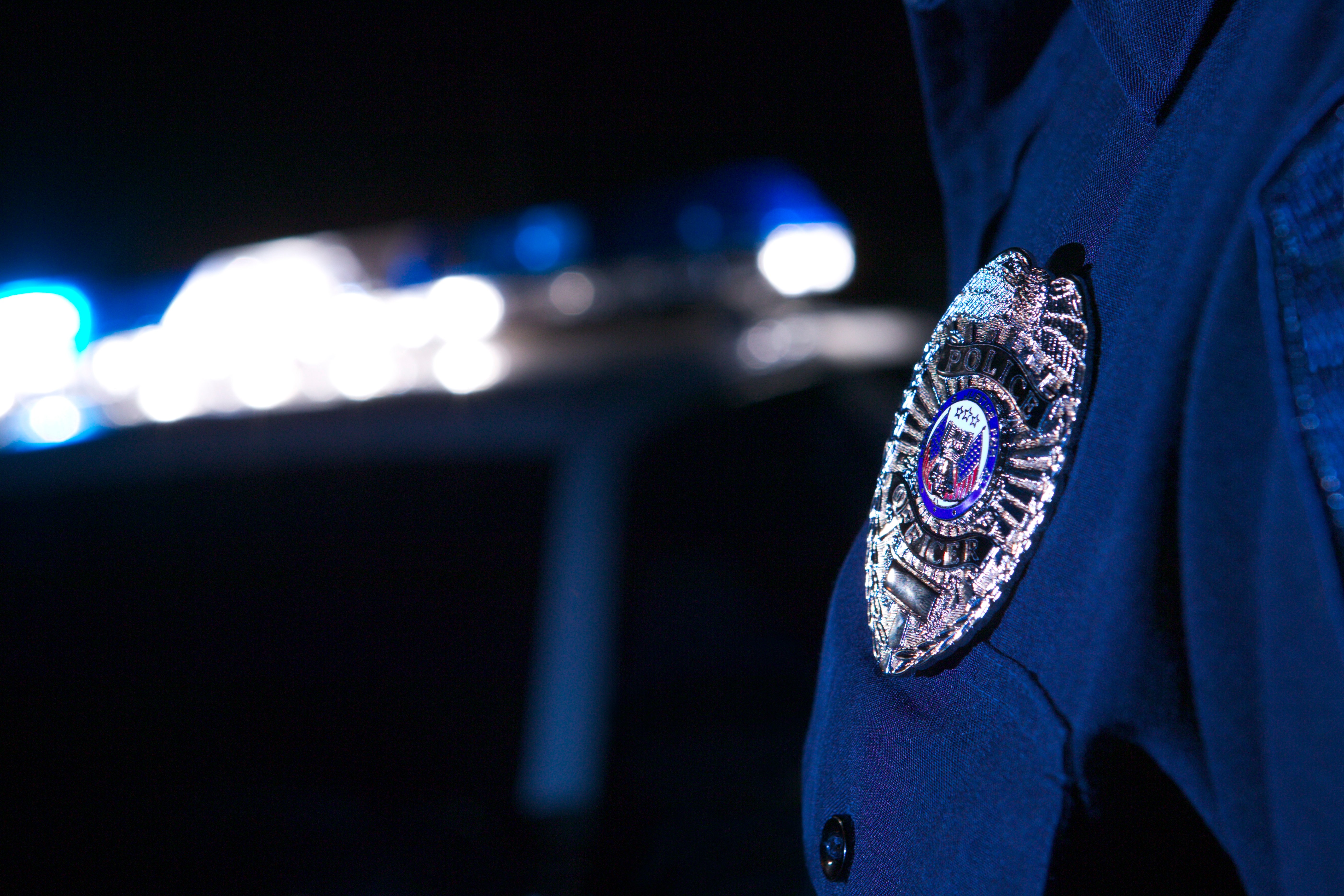 Closeup of police officers badge with car in background