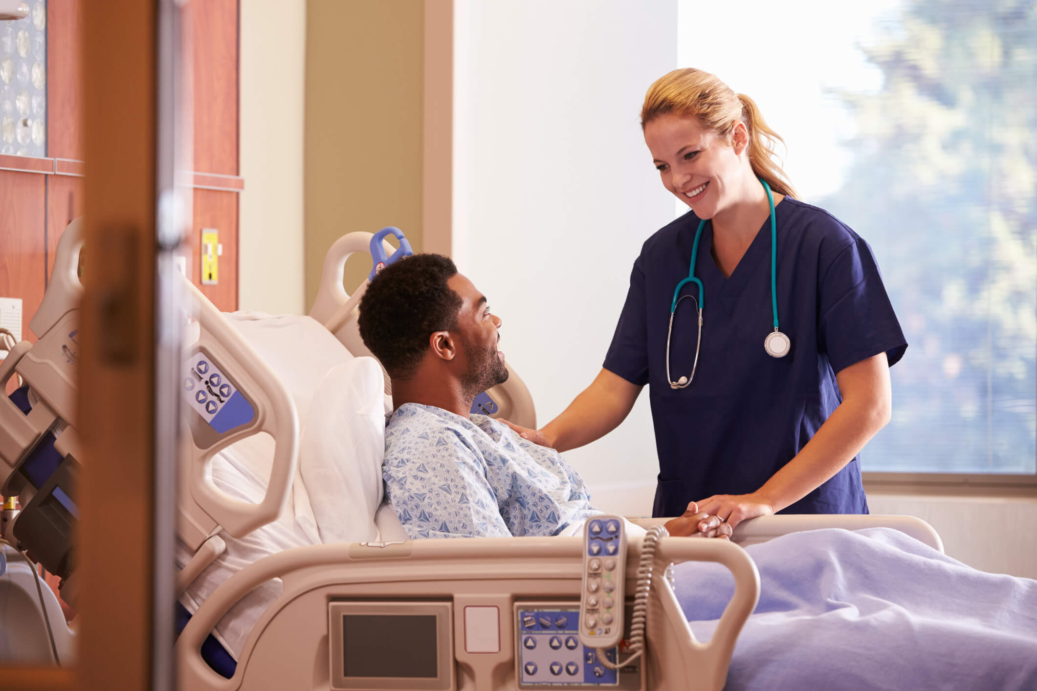 Female doctor talking to male patient in hospital bed