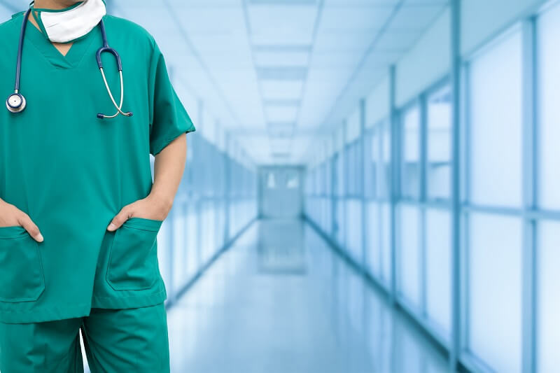 A physician in scrubs in a hospital hallway