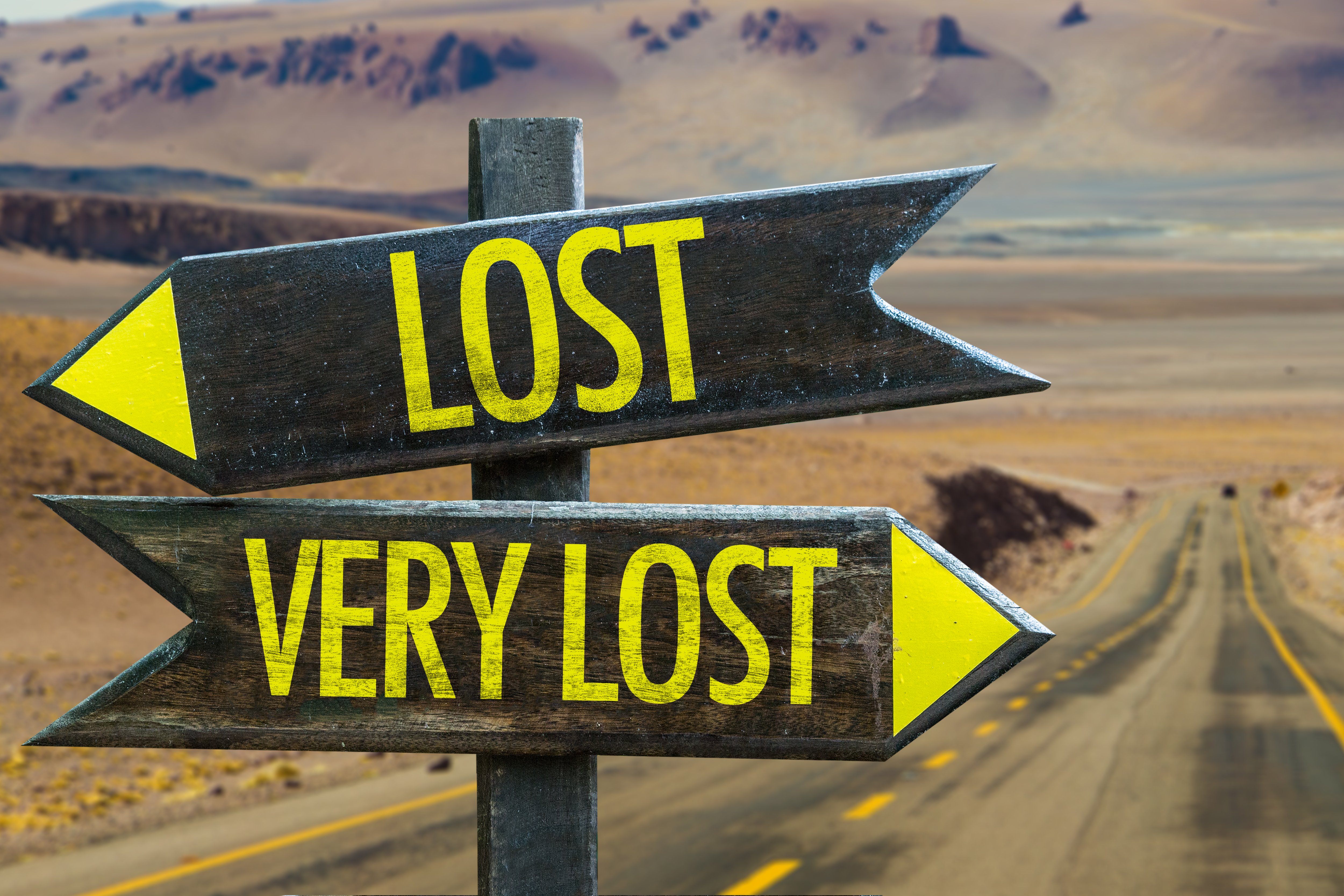 Two signs one reading lost and the other reading very lost pointing in opposite directions on a desert road