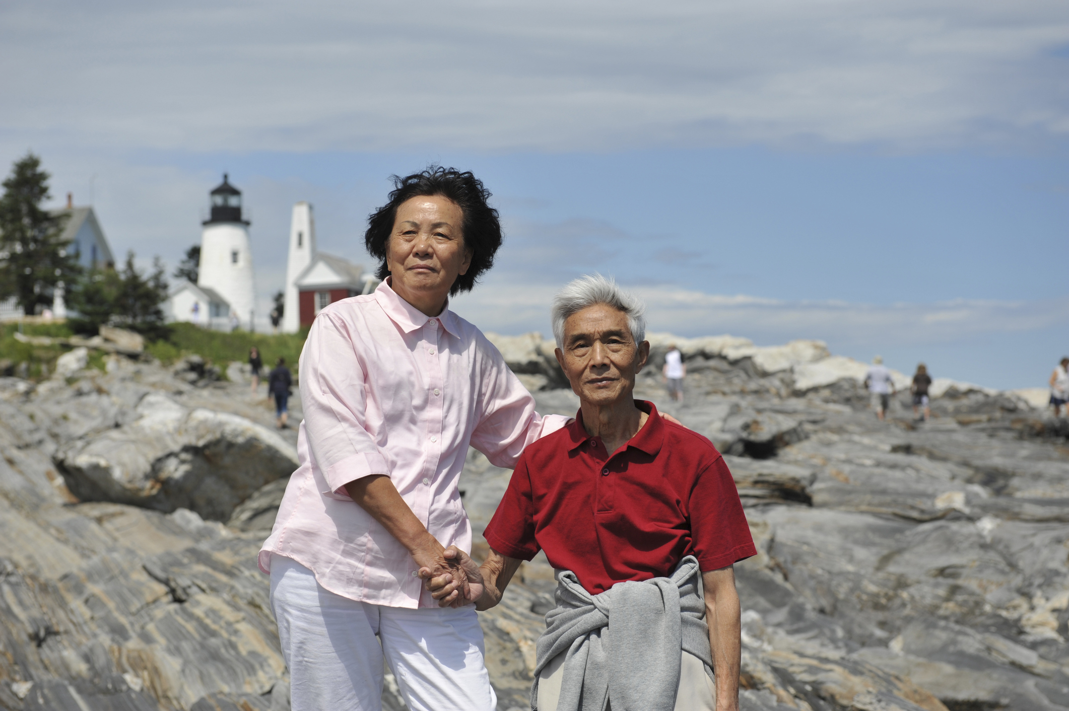 Senior couple at Pemaquid Point Maine -- lighthouse rocks and ocean visible in background