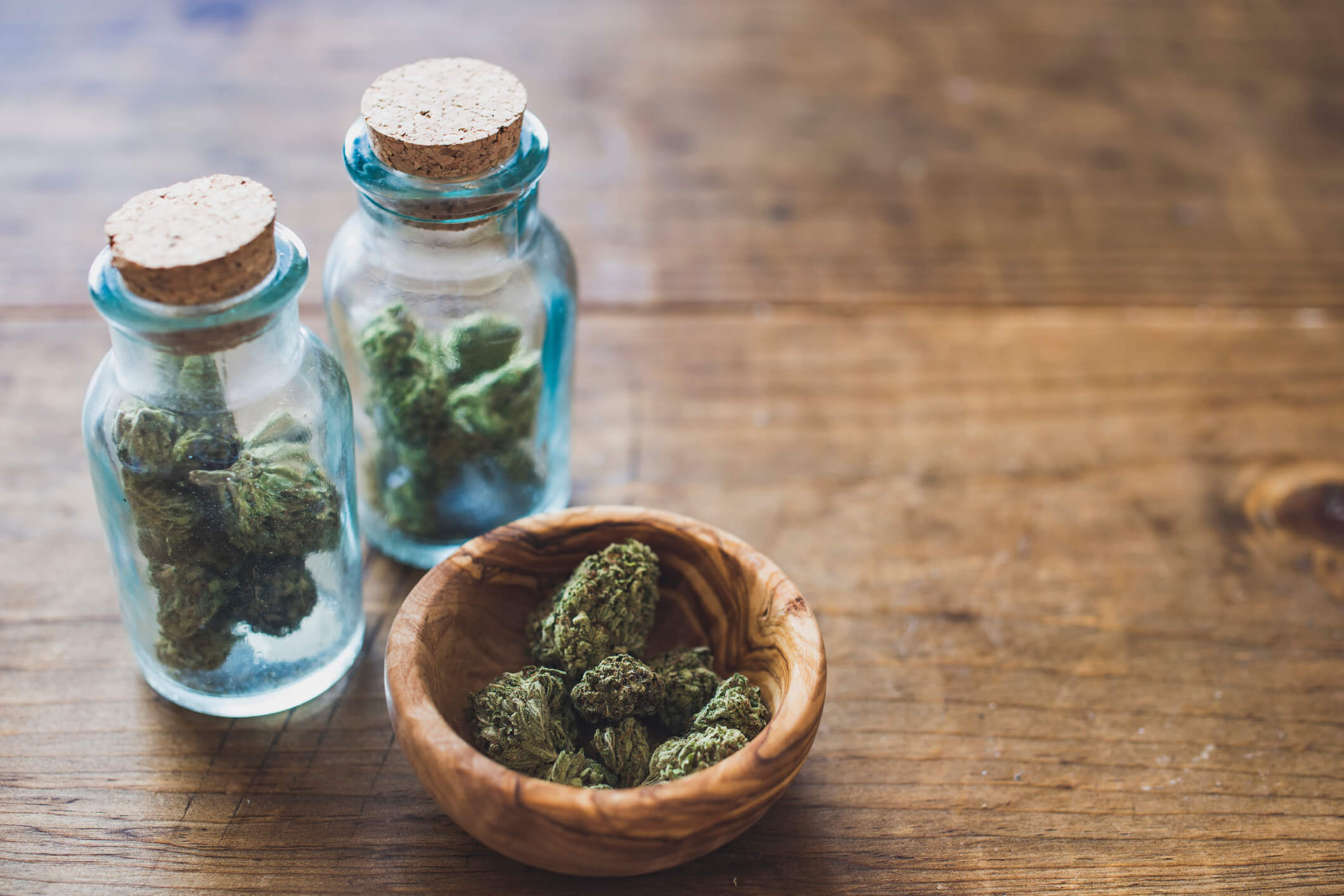 Marijuana in glass jars and wooden bowl