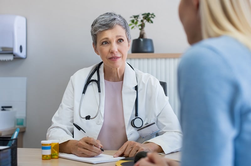A mature woman physician consulting with a patient in the doctors office 
