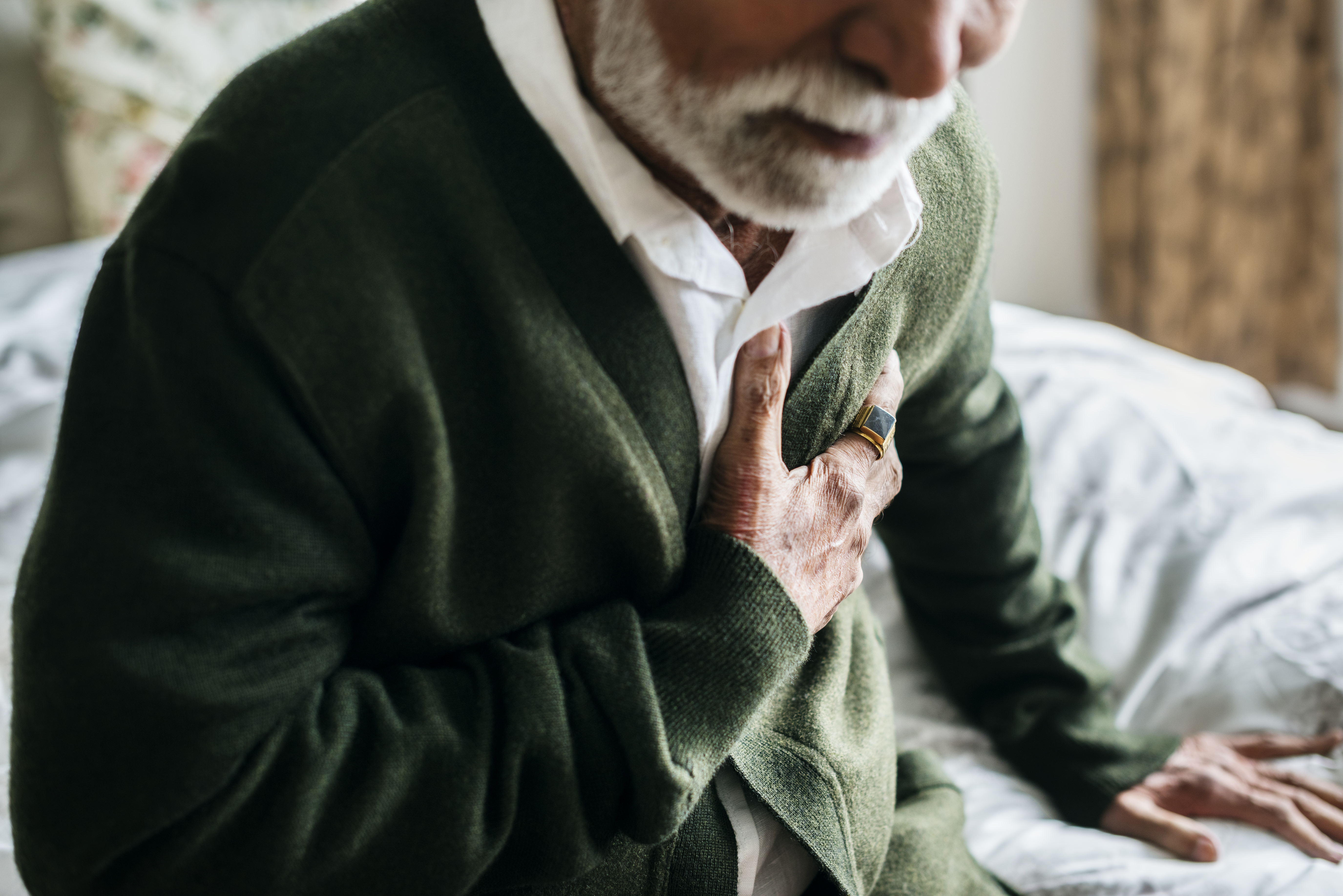photo of elderly man having heart problems holding his chest