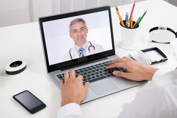 Businessman video-chats with doctor on laptop