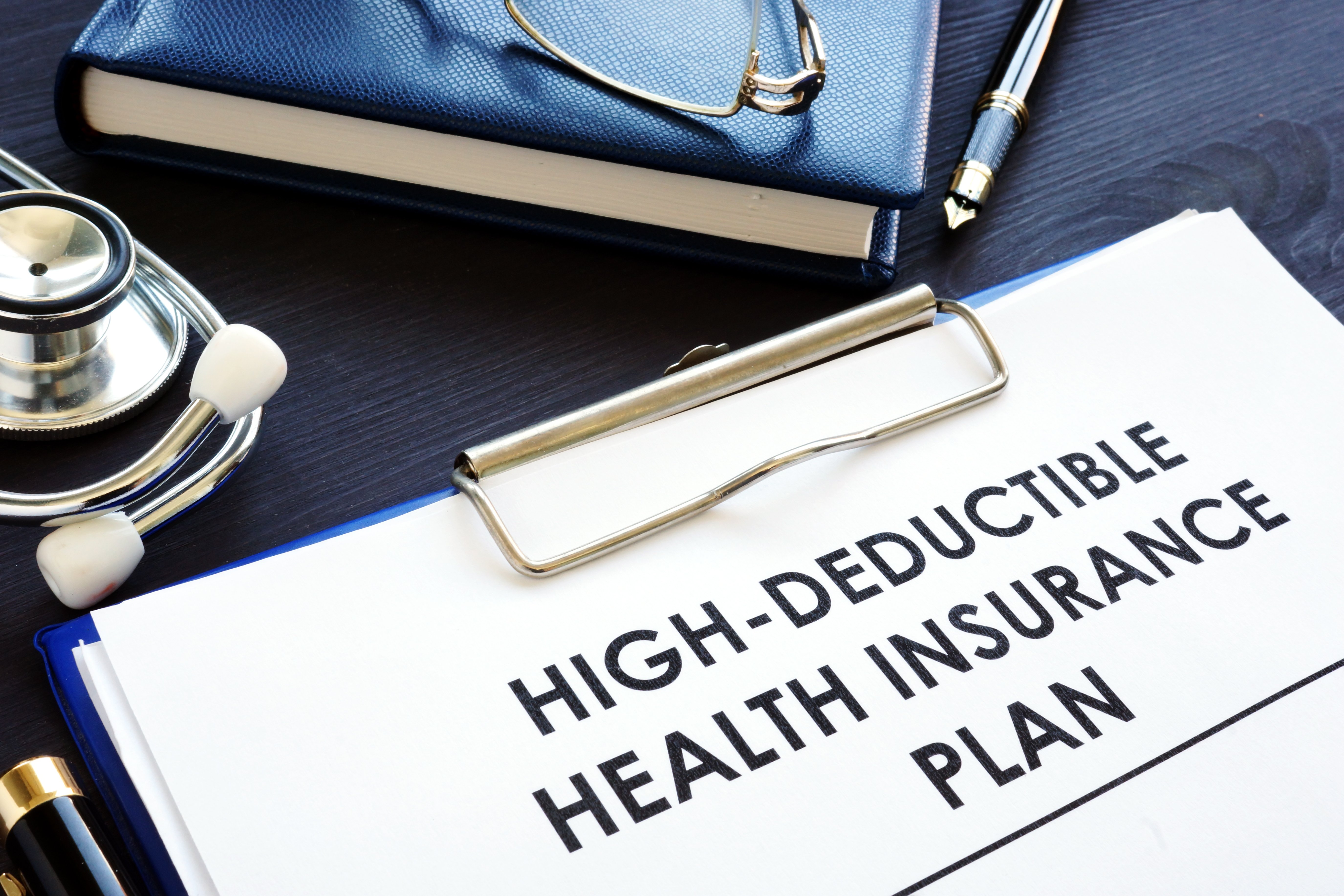 A clipboard with a paper reading High-deductible health insurance plan
