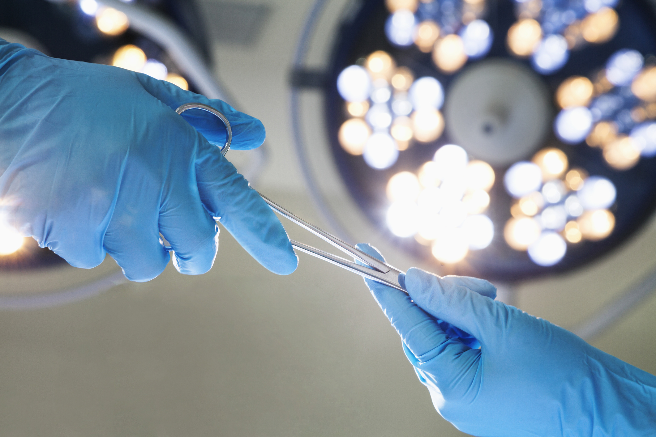 Close-up of gloved hands passing the surgical scissors