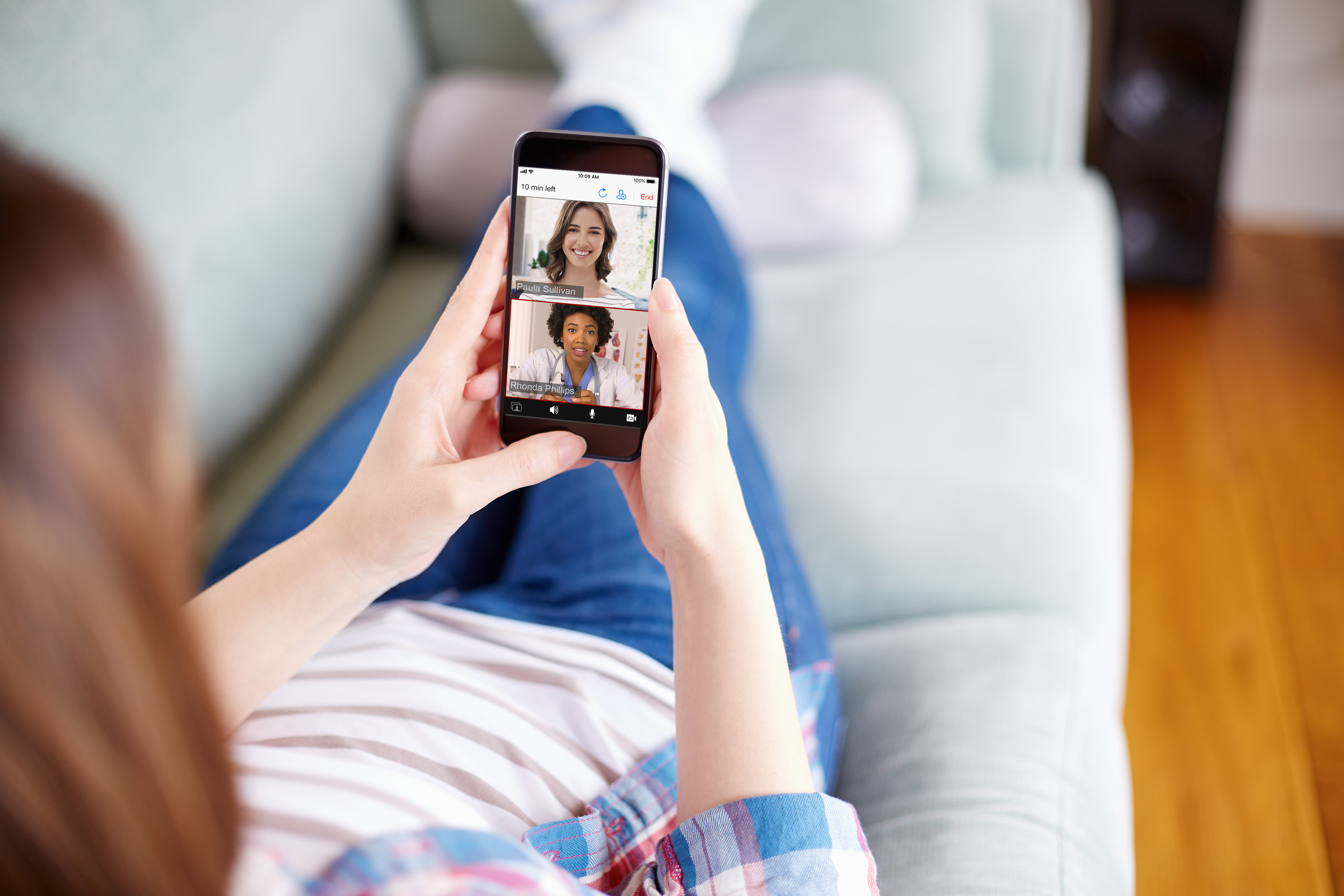 woman on couch uses telehealth app to talk to doctors