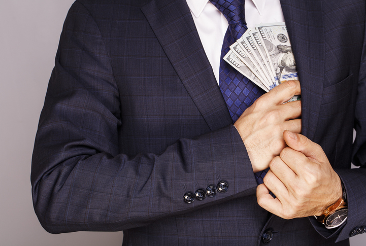 A business man puts money into his suit jacket