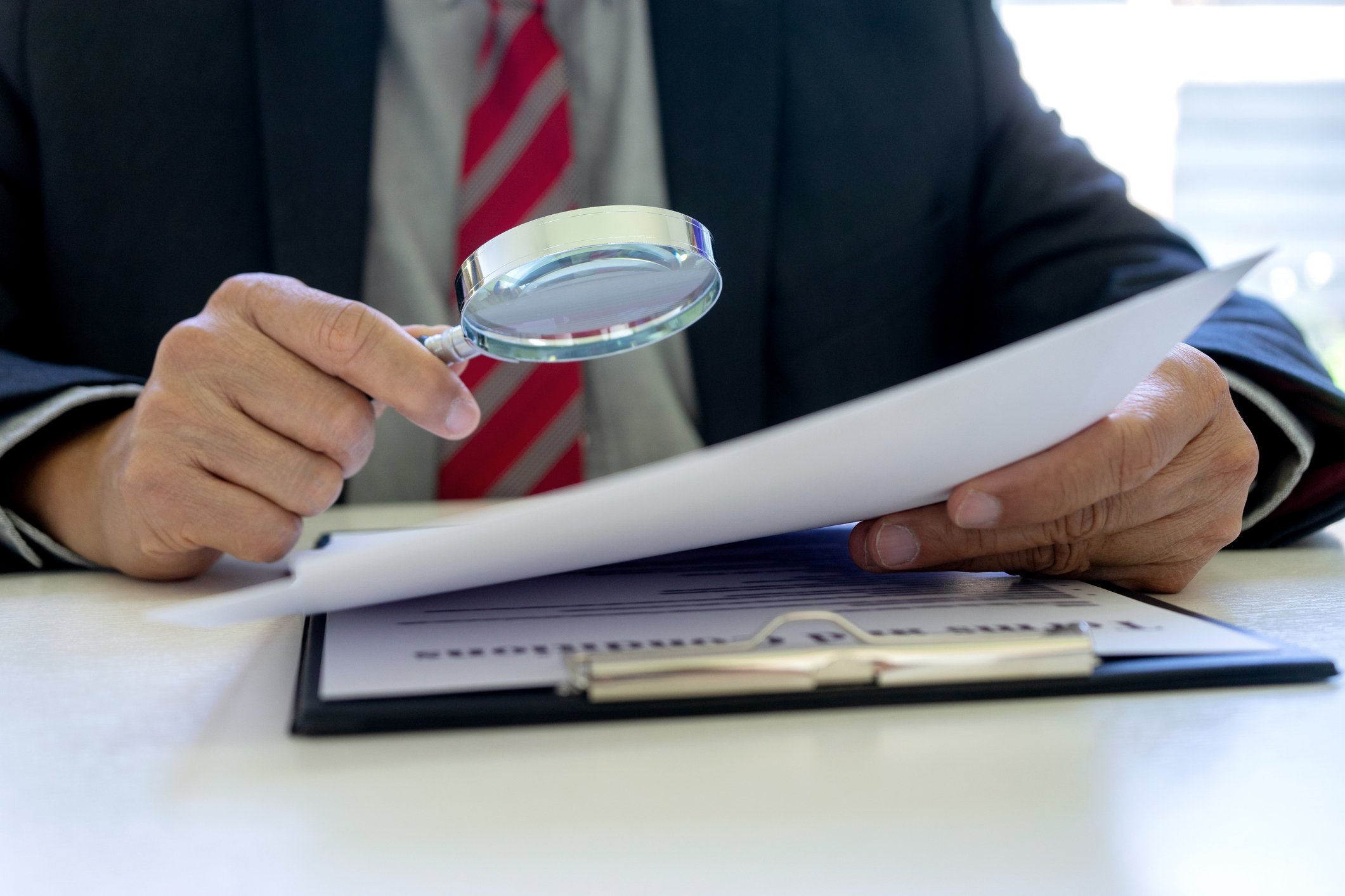 Person uses magnifying glass to inspect a document