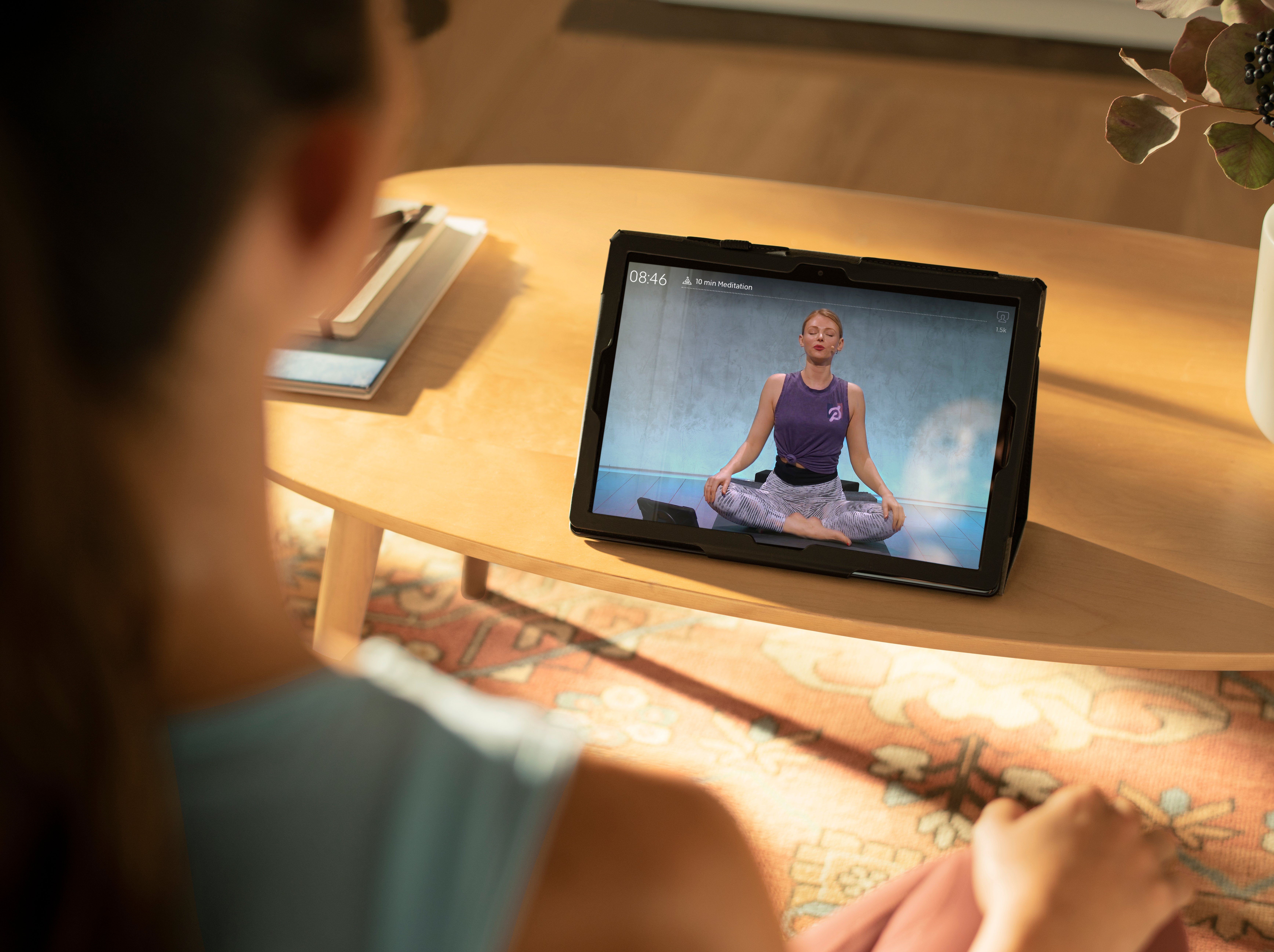 woman doing meditation exercises with laptop screen showing Peloton app