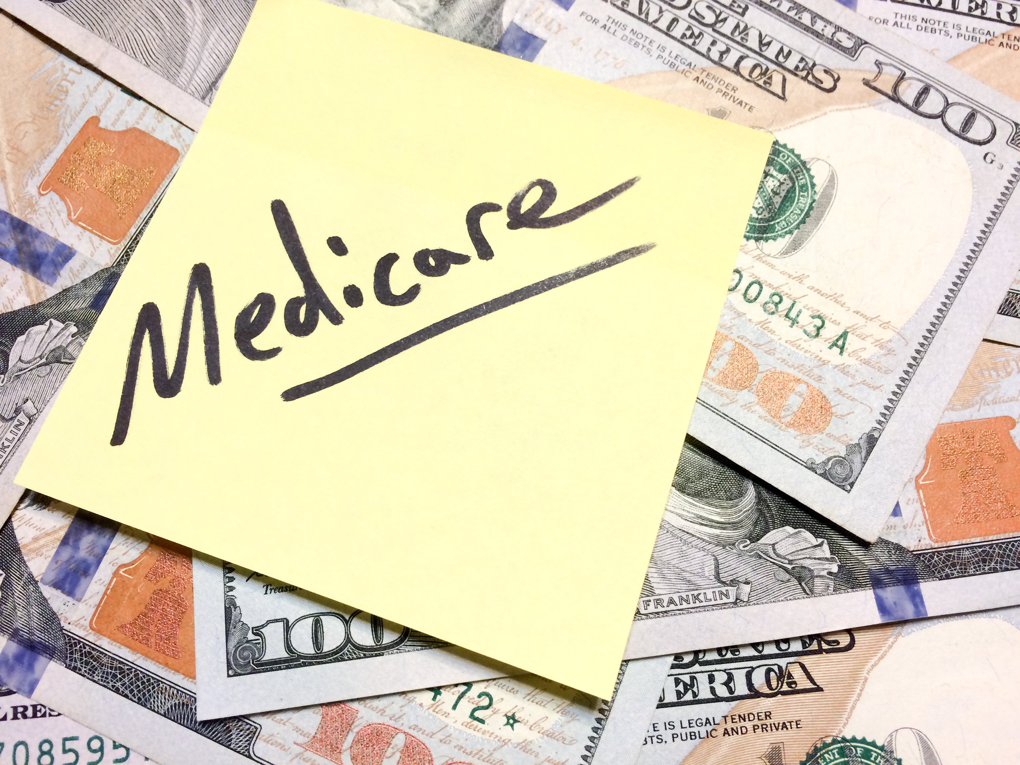 A sticky note says Medicare on top of a pile of money