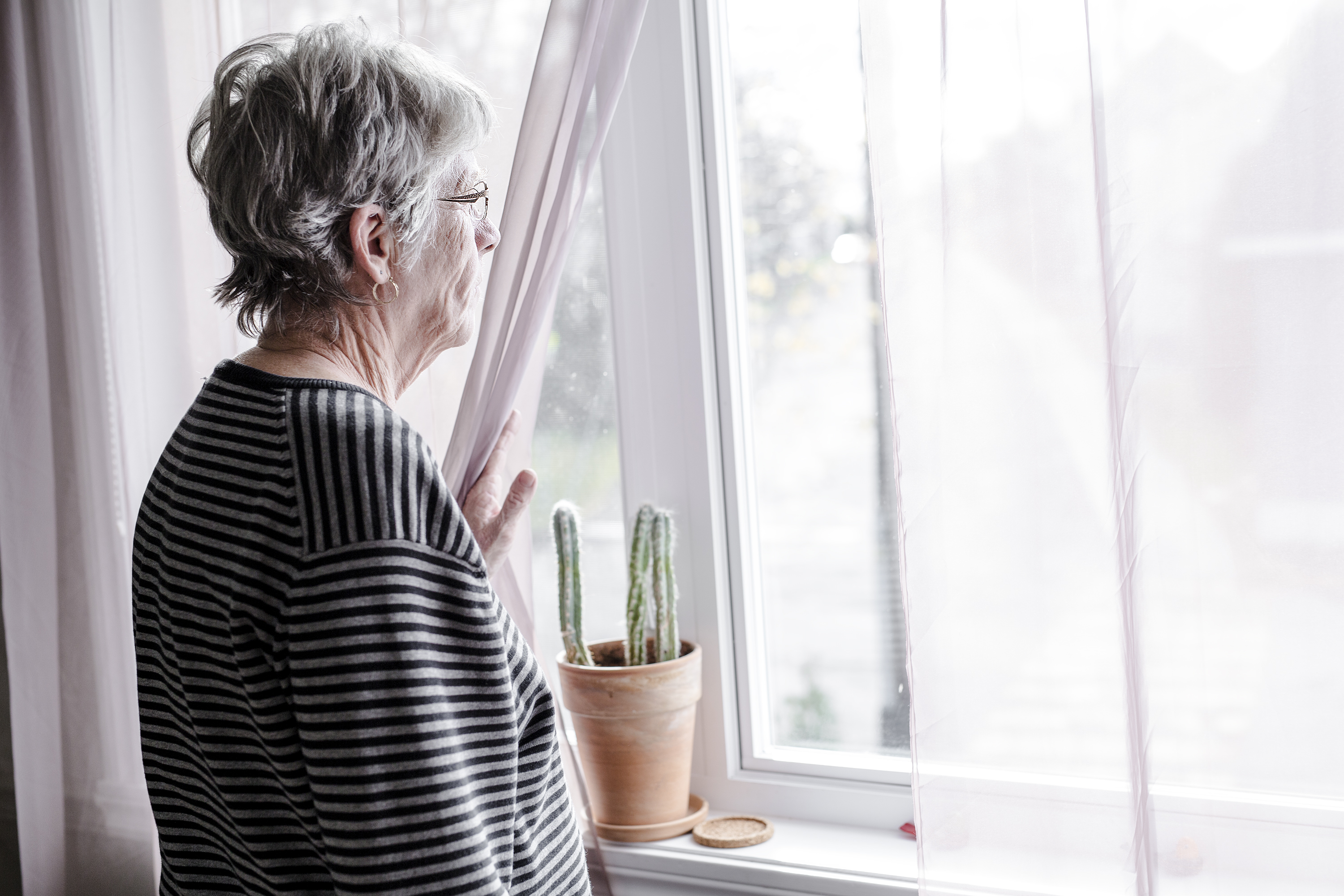 An elderly woman looking out a window