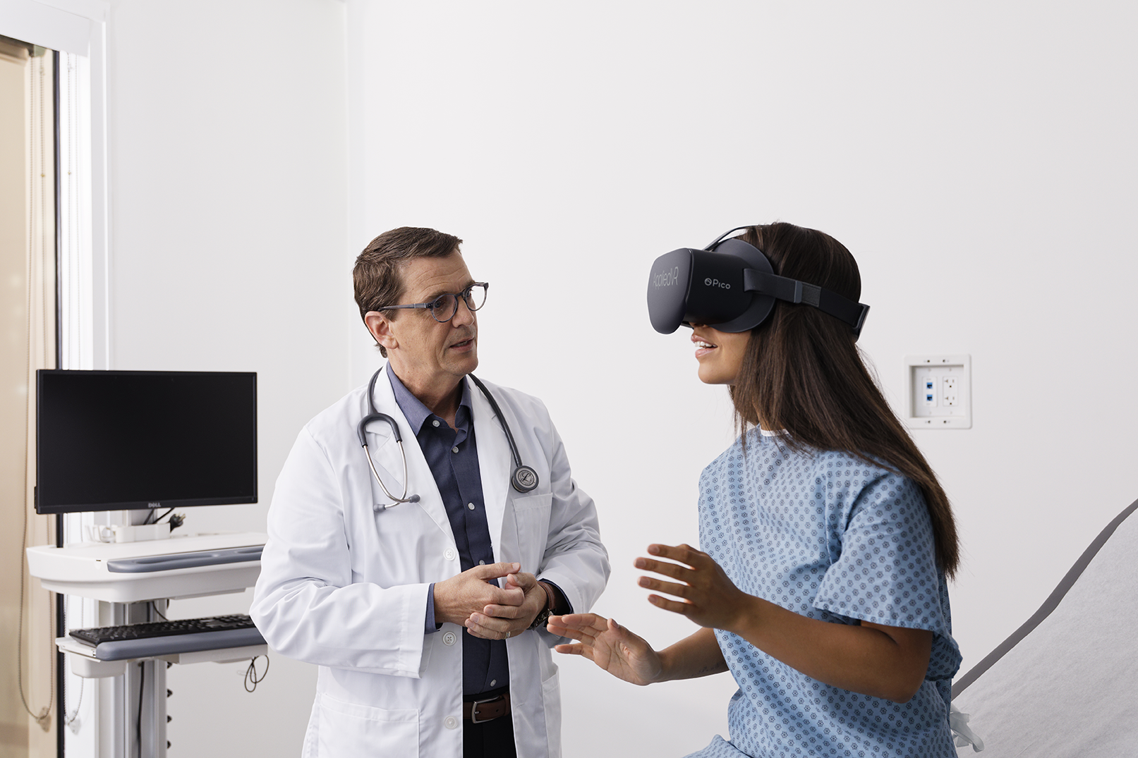 A doctor speaks to a female patient wearing a VR headset 