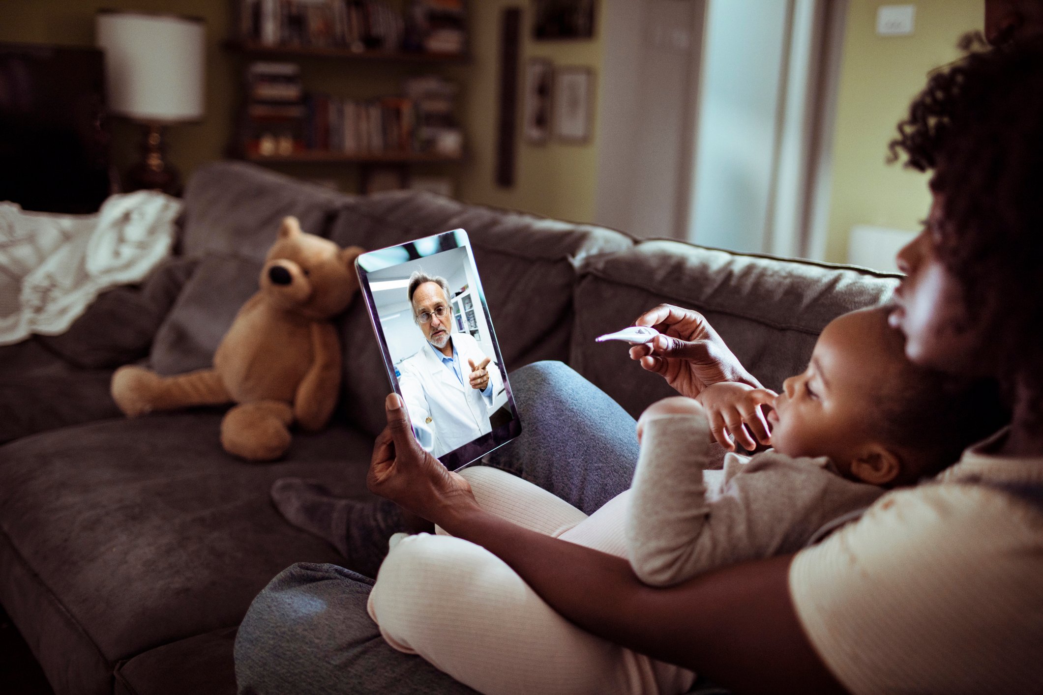 close up of a mother and daughter consulting with their doctor over a video call on their digital tablet