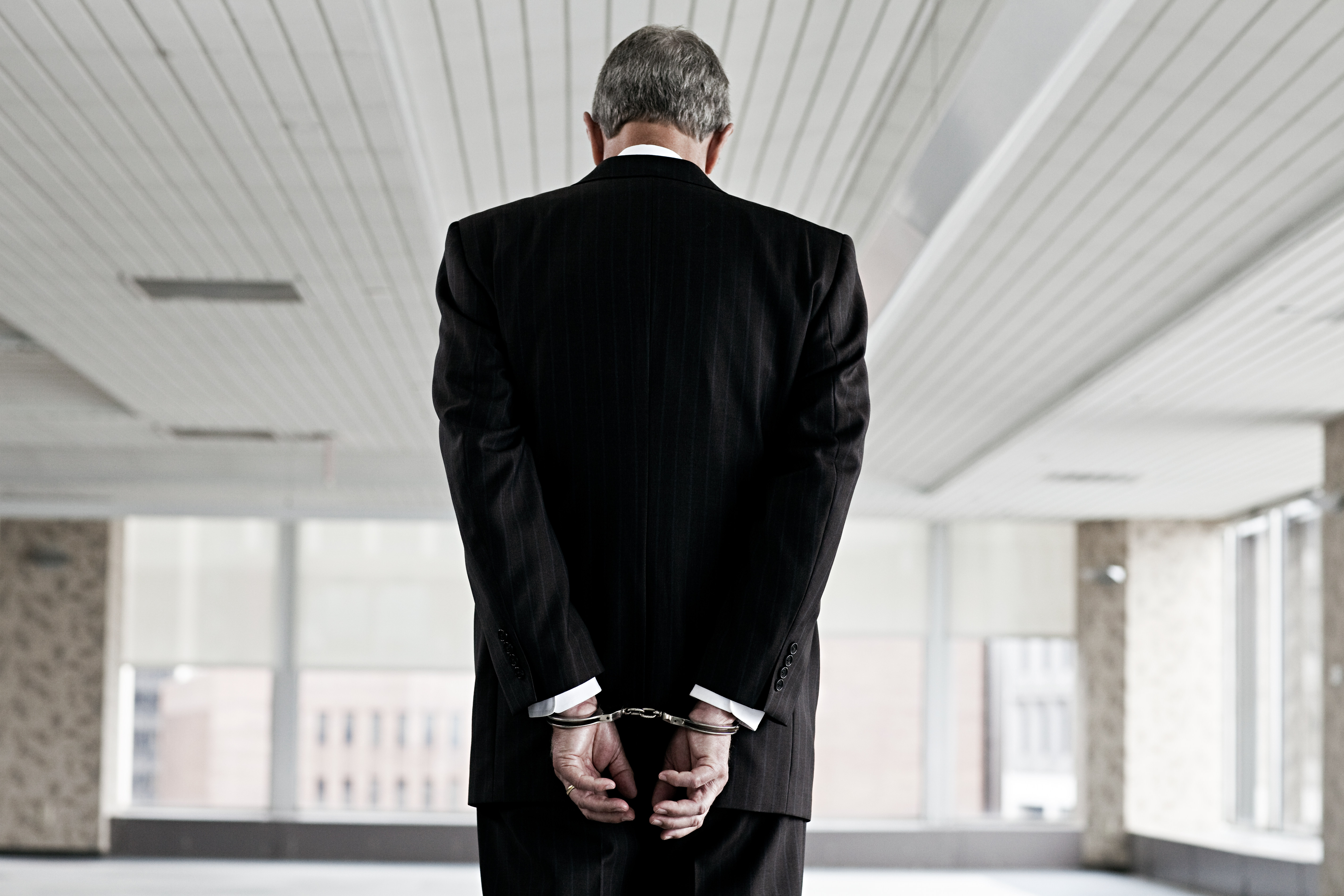 Businessman in handcuffs with his back turned