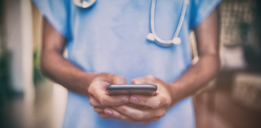 doctor in hospital hallway using smartphone