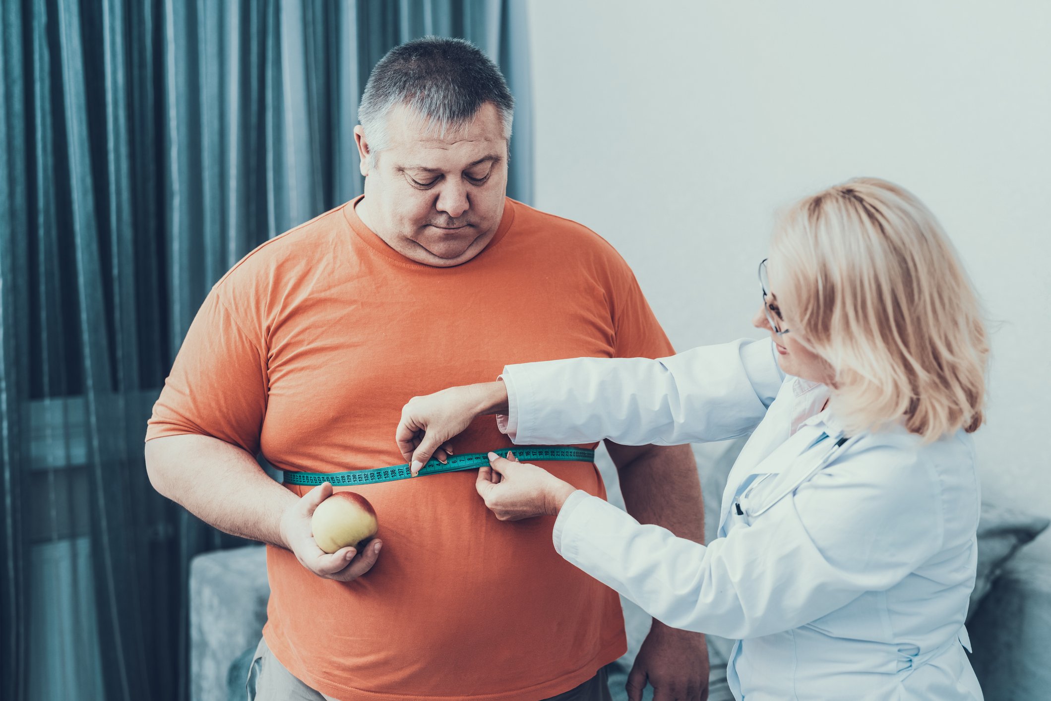 doctor measures the waist of an overweight male patient