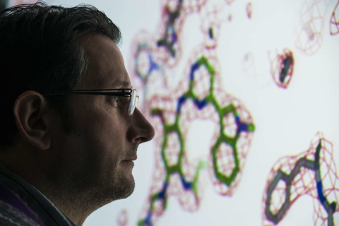 Male scientist looks at large screen