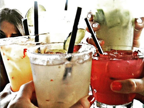 Hands holding glasses filled with margaritas