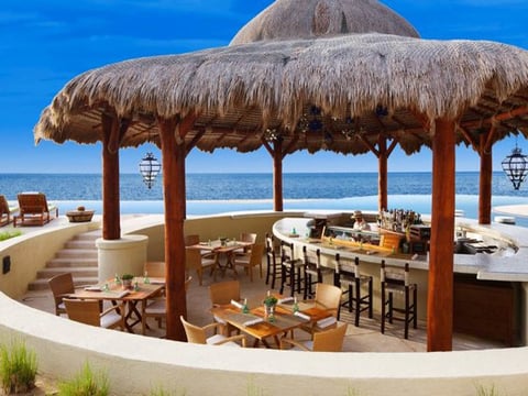 An outside eating area with a canopy and seats around a bar
