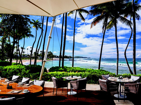Tables and chairs set outside underneath umbrellas