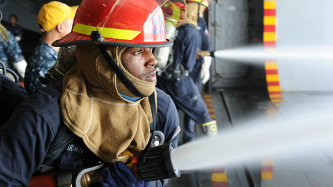A fireman holding a firehose that is open and expelling water