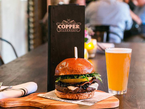 A table with a hamburger and a glass of beer